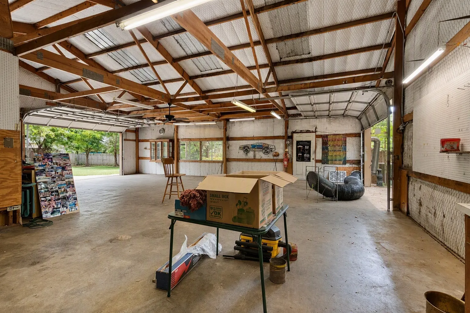 Expansive 40 x 40 ft shop space multiple garage doors, concrete floor, exposed beam ceiling, multiple overhead fluorescent lights, industrial heat pump HVAC, a separate office area and room to park up to 6 vehicles.