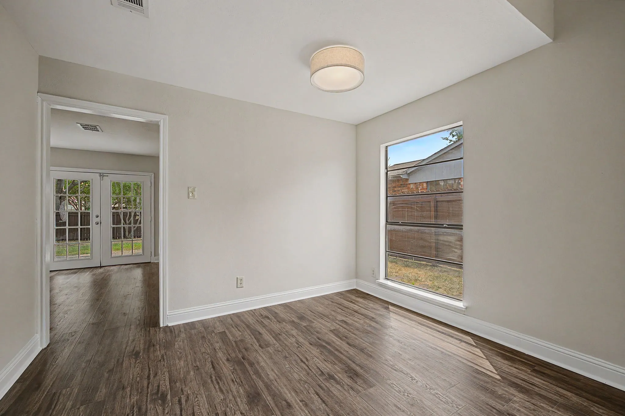 Dining room has a decorative drum light fixture and large window.