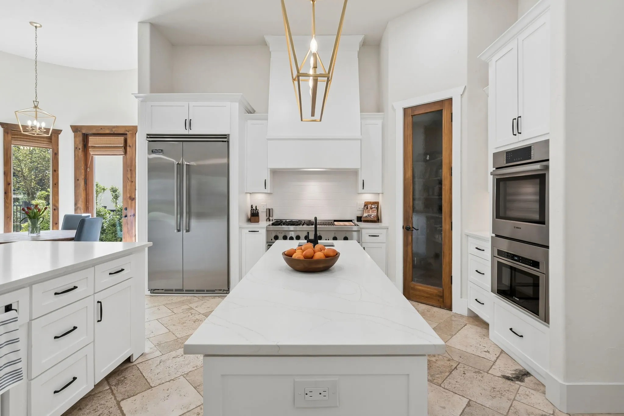 Gourmet kitchen with white cabinetry, stainless steel appliances, dual islands, tiled flooring, and a walk-in pantry