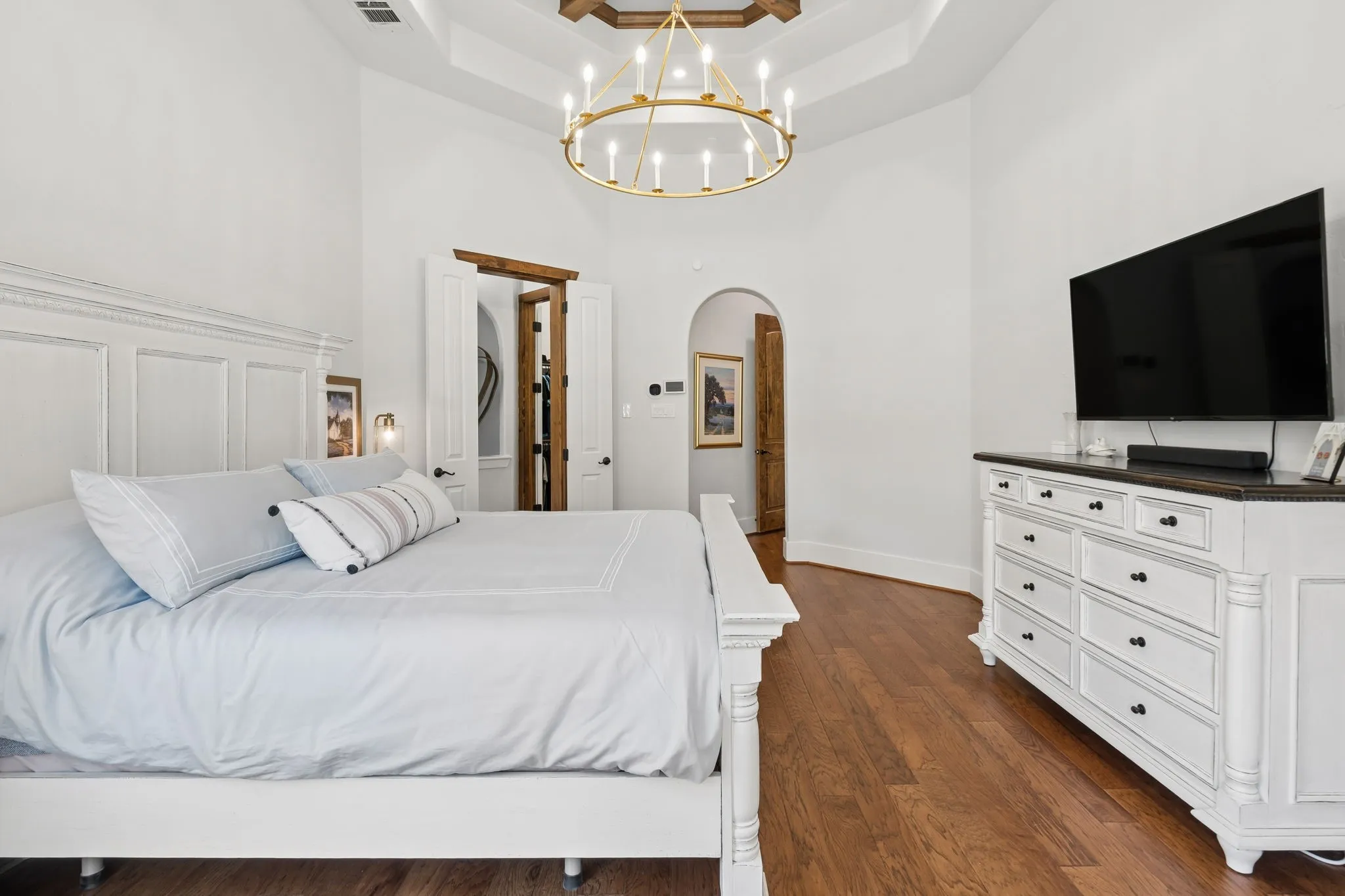 Tray ceiling with wood-beam accents and a chandelier light fixture