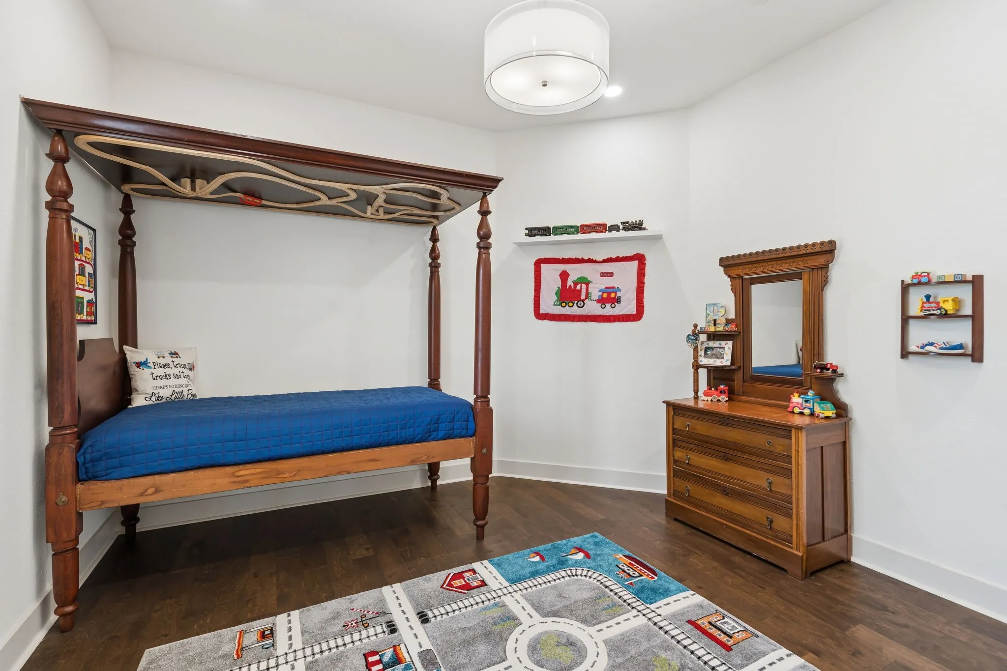 Hardwood-style flooring, white walls, and a drum ceiling light fixture