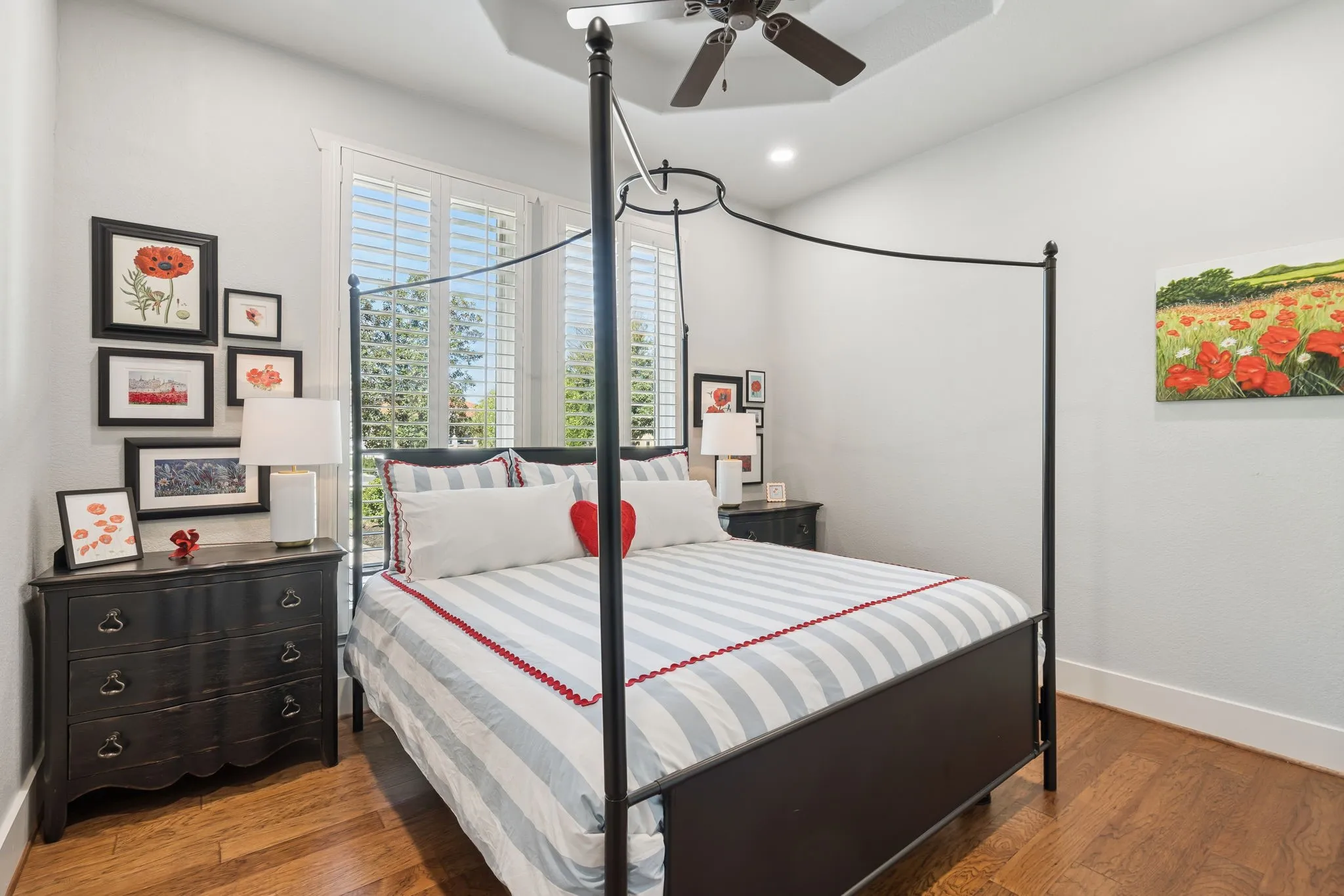 Hardwood flooring, plantation shutters, tray ceiling, recessed lighting, and a ceiling fan