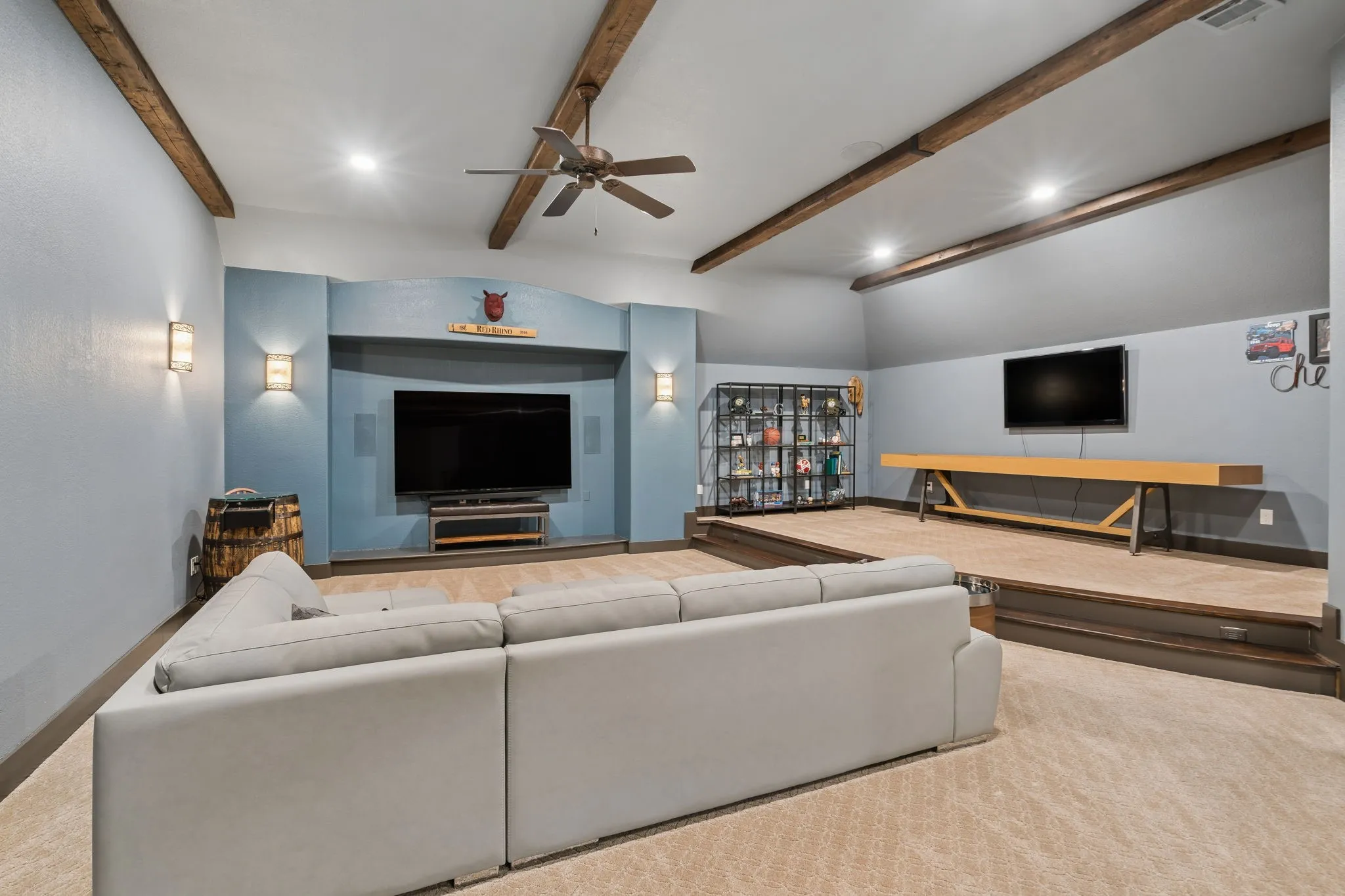 Spacious entertainment area with exposed ceiling beams and recessed lighting