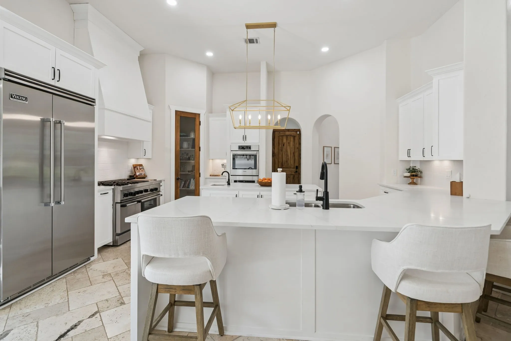 Spacious kitchen featuring an island with counter seating, stainless steel appliances, white cabinetry, and a walk-in pantry