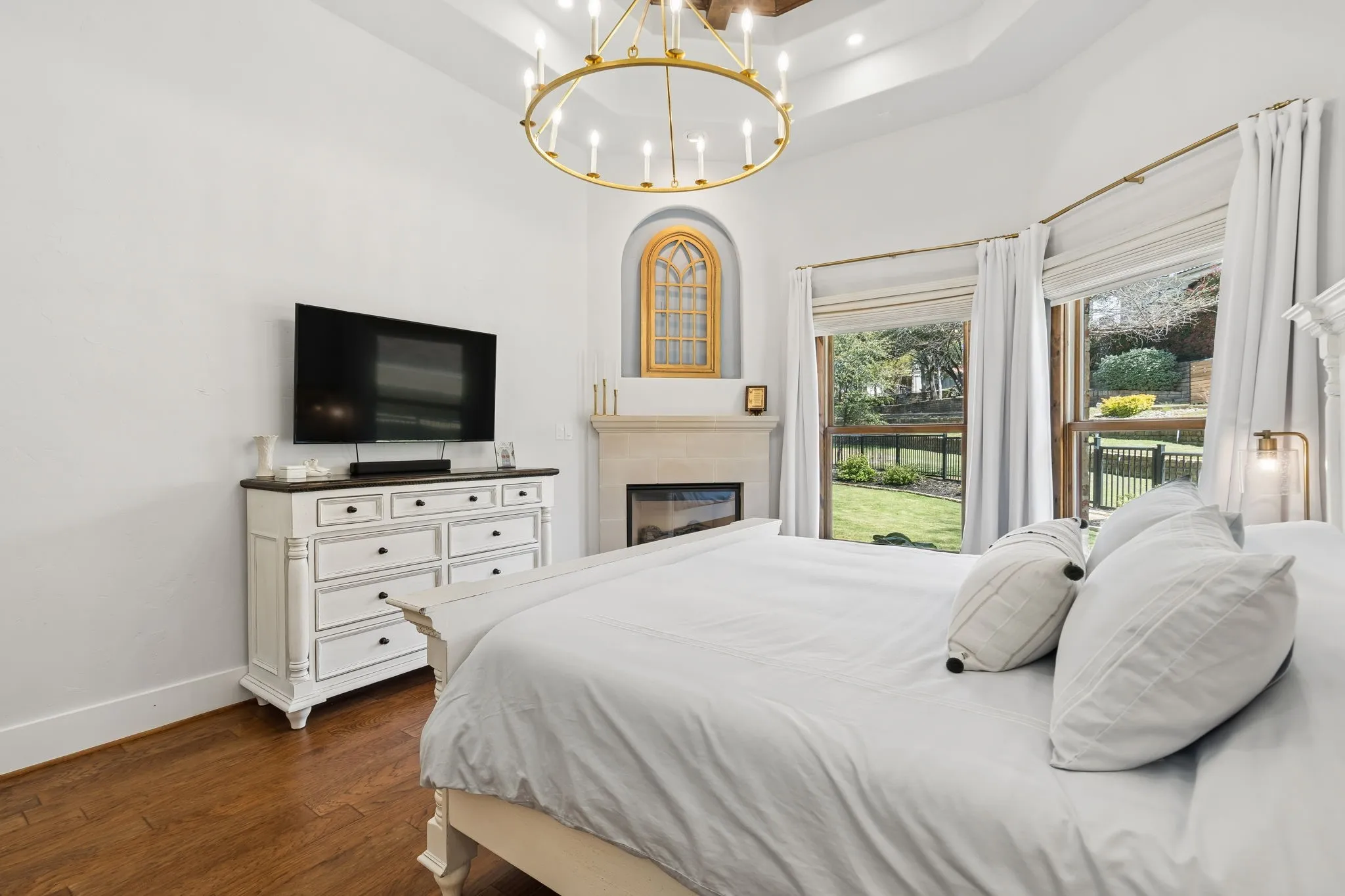 Hardwood flooring, tray ceiling, fireplace, recessed lighting, and a gold-finish chandelier