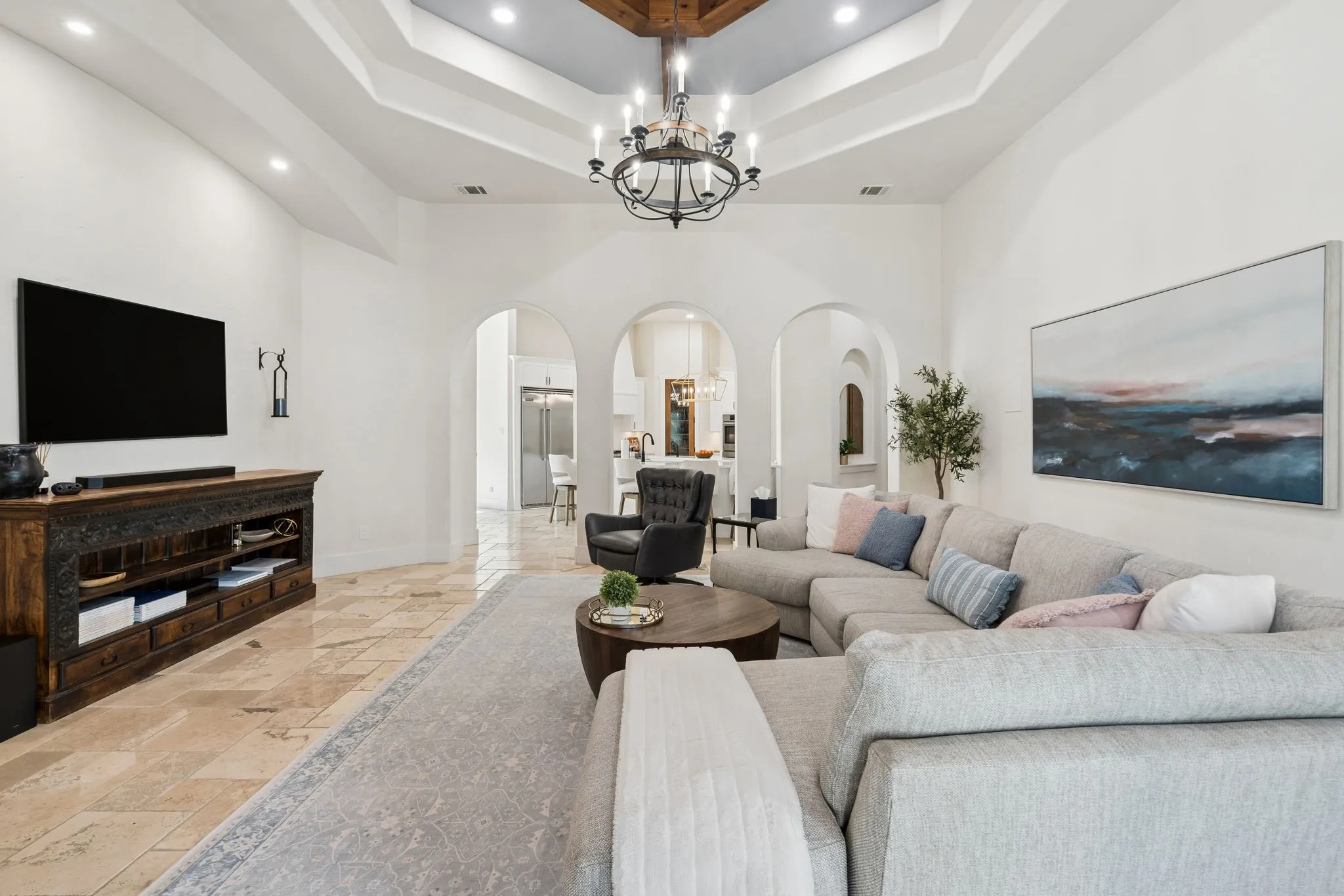 Spacious living area featuring a coffered ceiling, recessed lighting, and an ornate chandelier