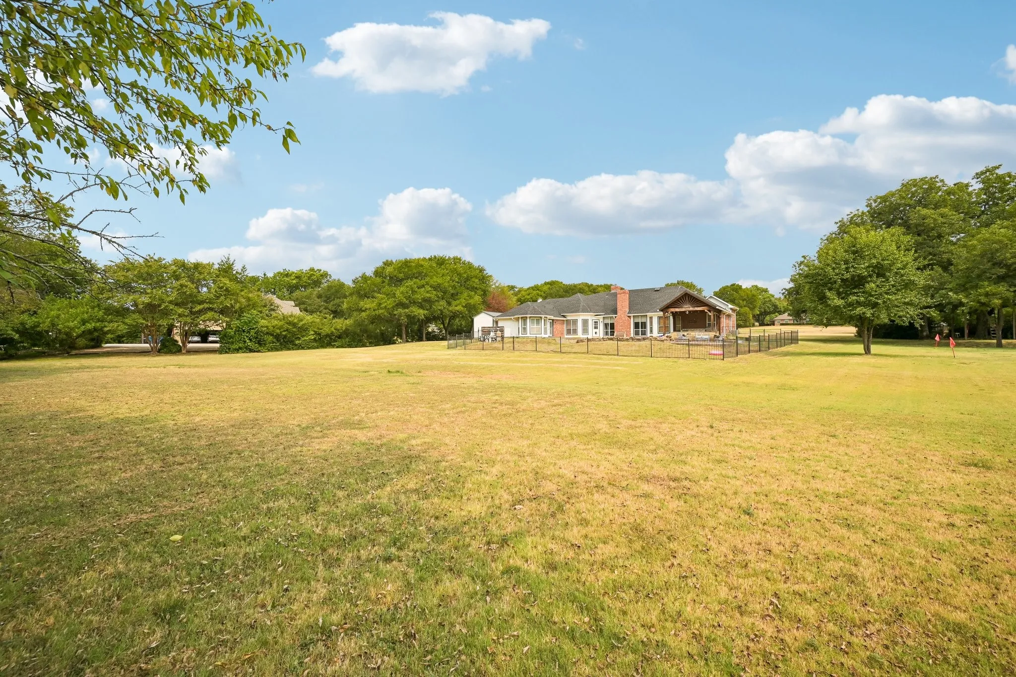 Expansive lawn featuring perimeter fencing and mature trees