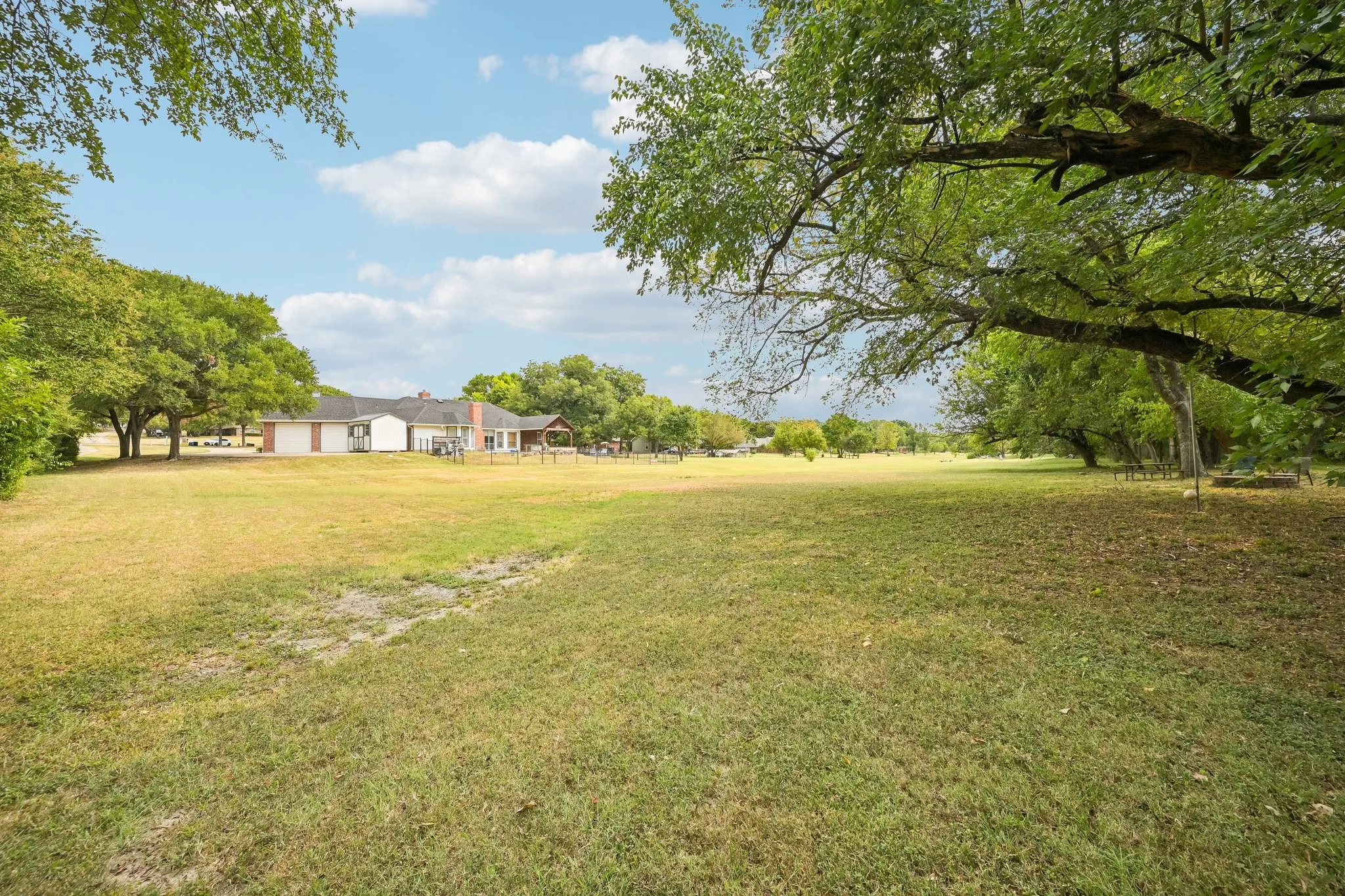 Expansive grounds featuring mature oak and shade trees, manicured lawn, and a single-story residence set back from the property line