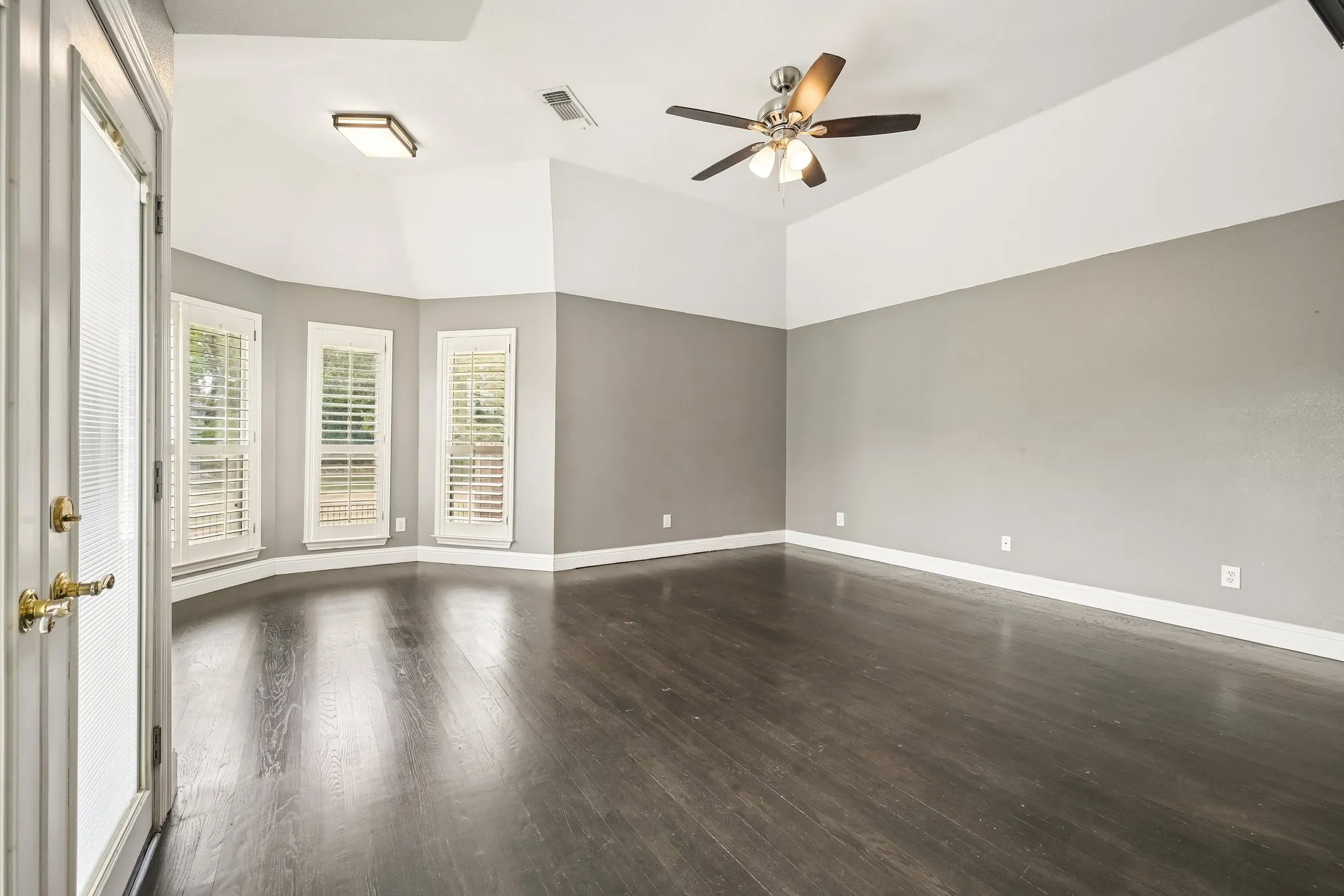 Wood-finish flooring, vaulted ceilings, and a ceiling fan with integrated lighting