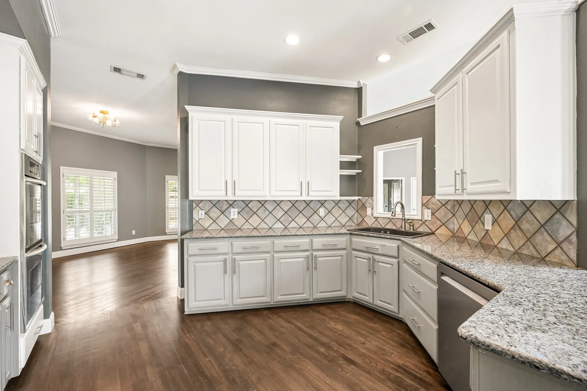 Elegant kitchen showcasing white cabinetry, stainless steel appliances, and a geometric tile backsplash
