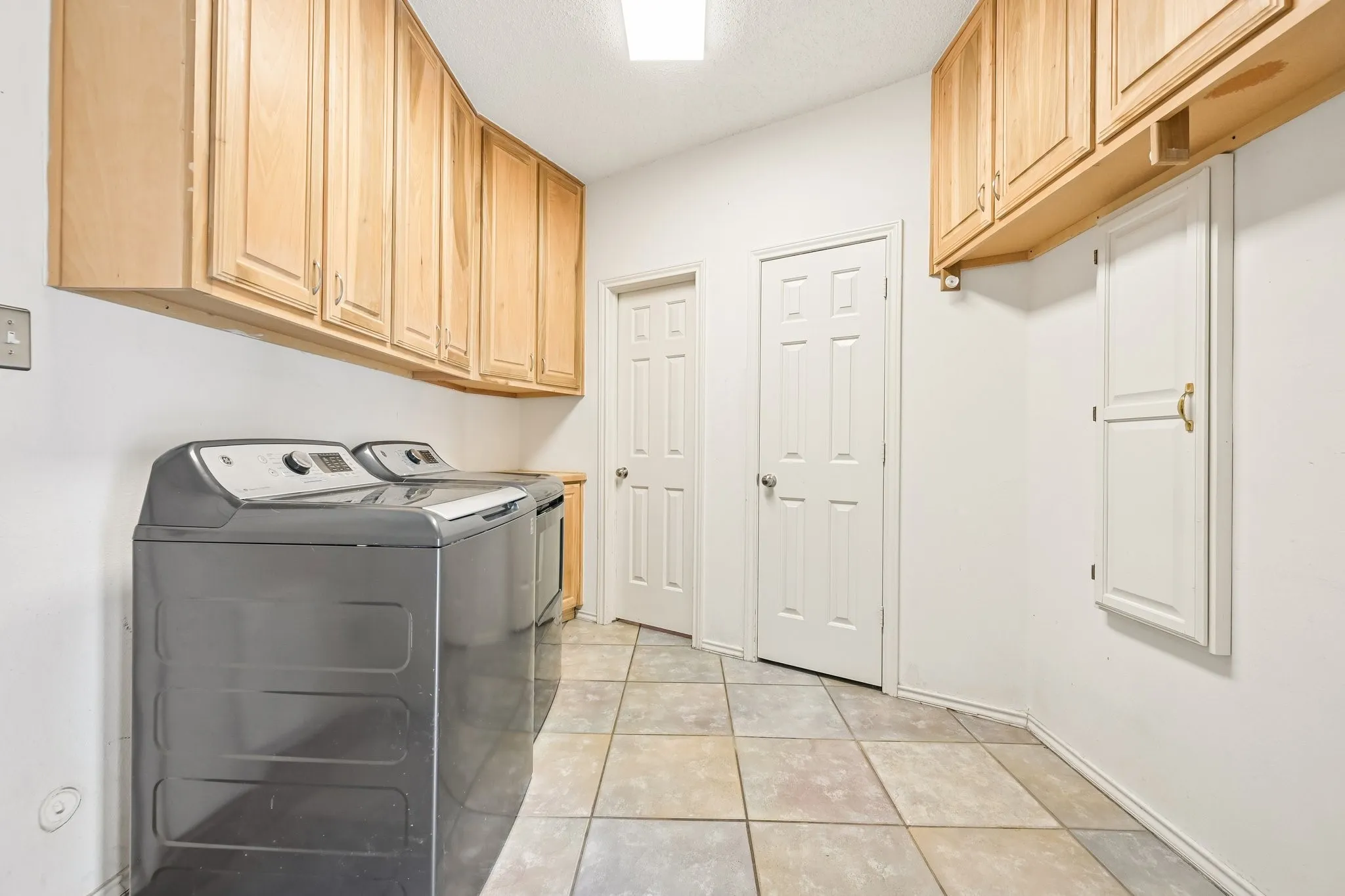 Extensive overhead cabinetry, durable tile flooring, and multiple paneled doors