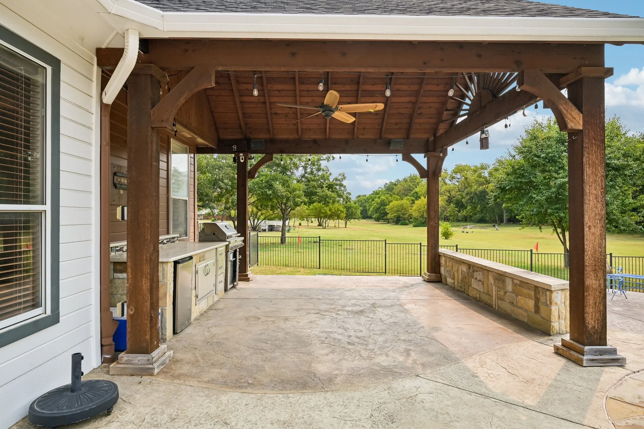 Covered patio featuring a wood-beam pergola, ceiling fan, and string lighting