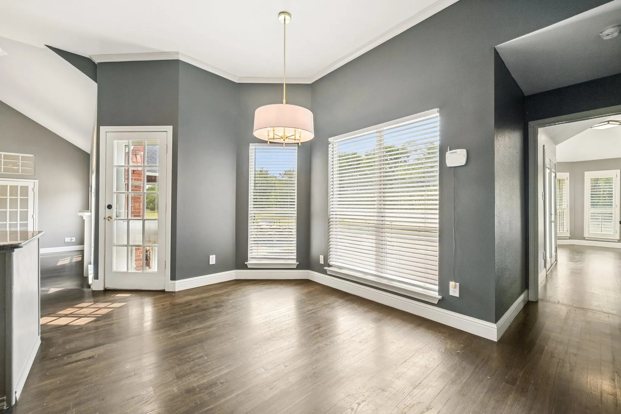 Wood-finish flooring, recessed lighting, and a drum pendant light fixture illuminate the interior