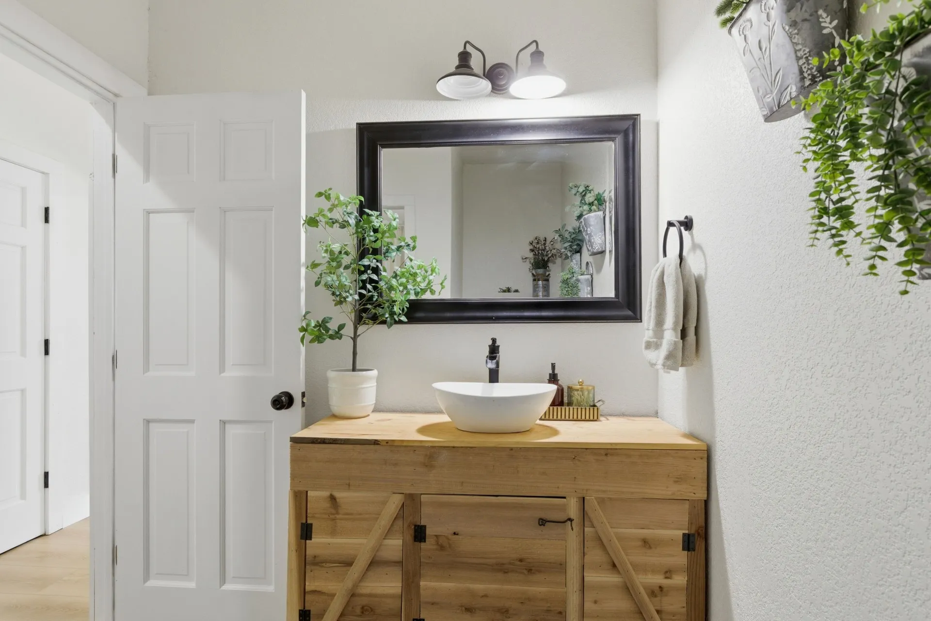 Wood-finish vanity with barn door style cabinetry, countertop vessel sink, and matte black faucet