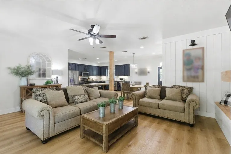 Wood-finish flooring, white walls, and a ceiling fan with integrated lighting