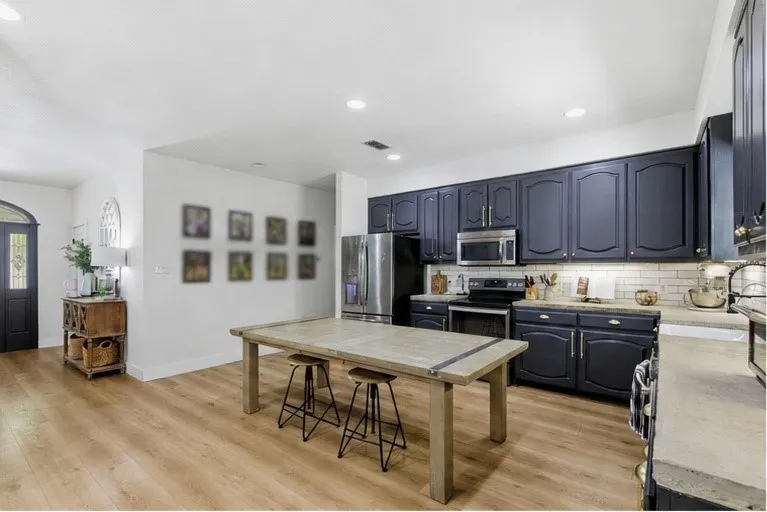 Kitchen featuring dark cabinetry, stainless steel appliances, a subway tile backsplash, and light-toned countertops