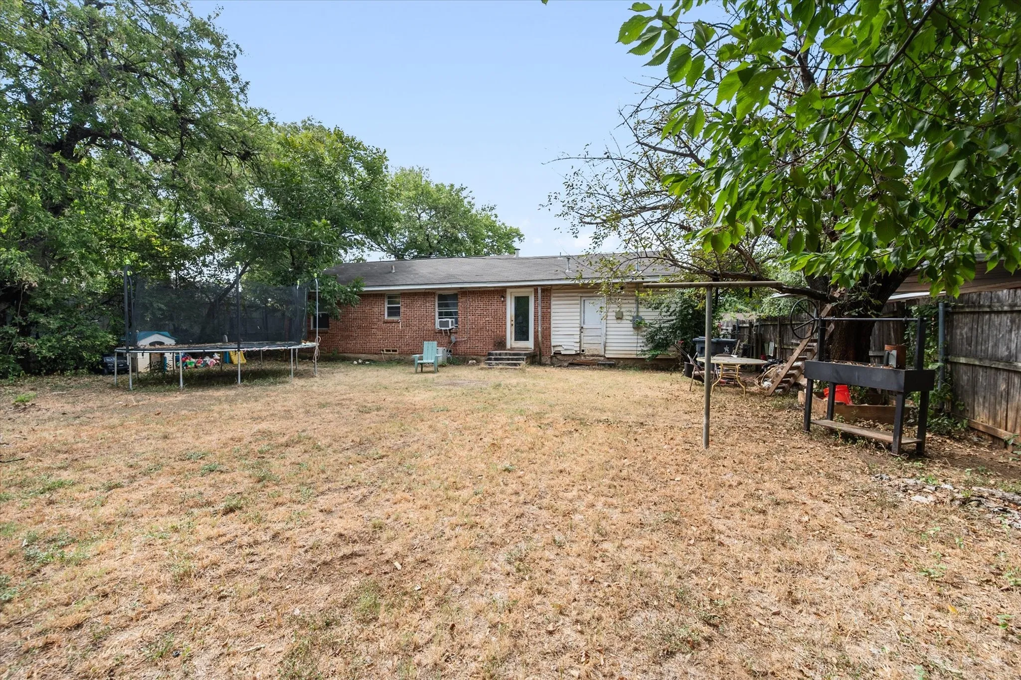 Expansive backyard featuring mature trees and a privacy fence
