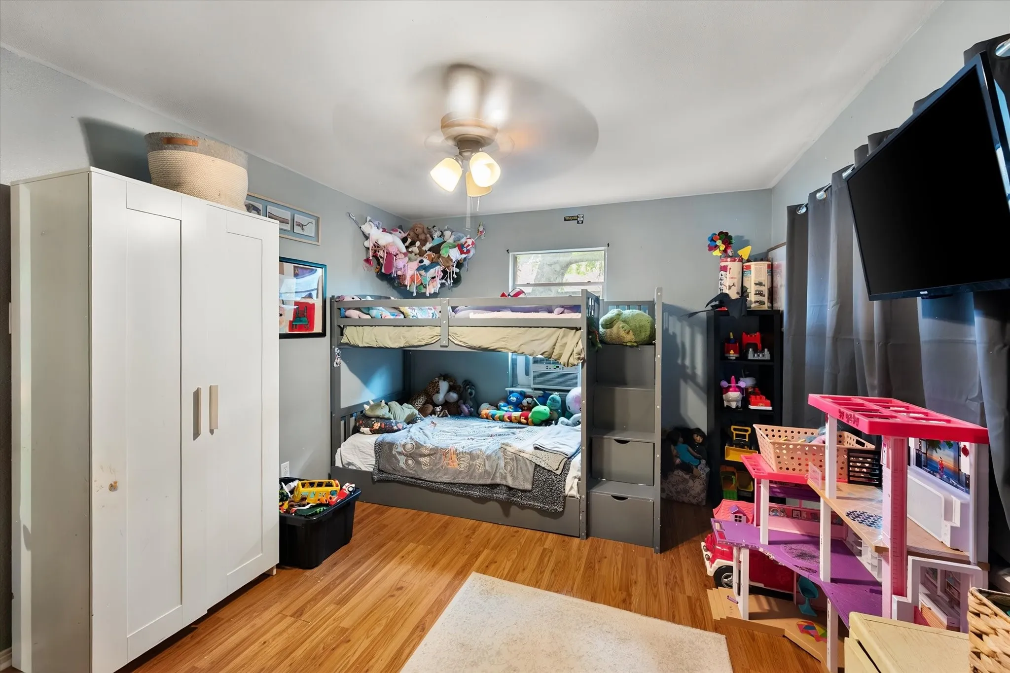 Wood-finish flooring, ceiling fan, built-in bunk bed with integrated storage, and window with natural light