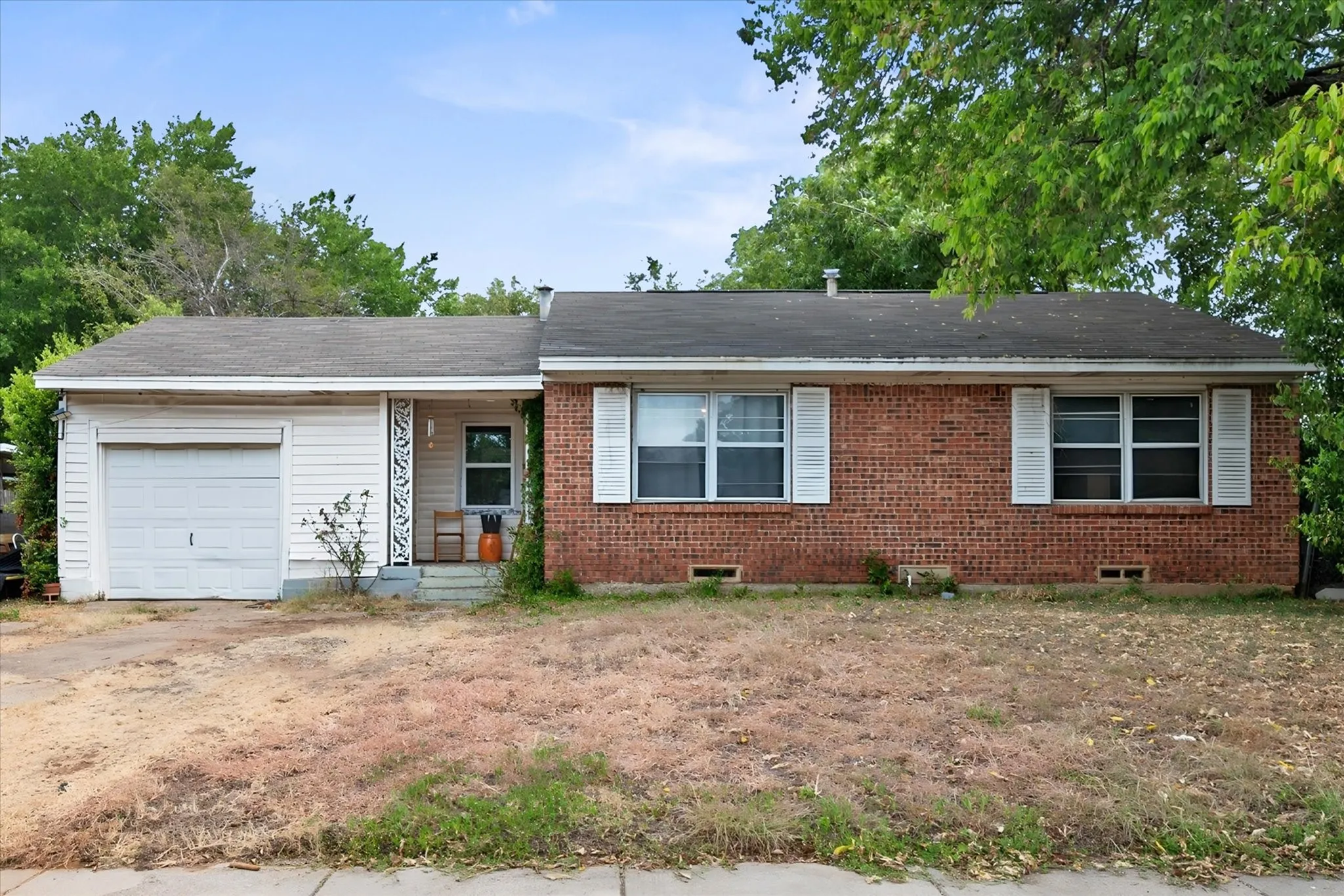 Brick and siding exterior with an attached single-car garage, front porch, and front yard
