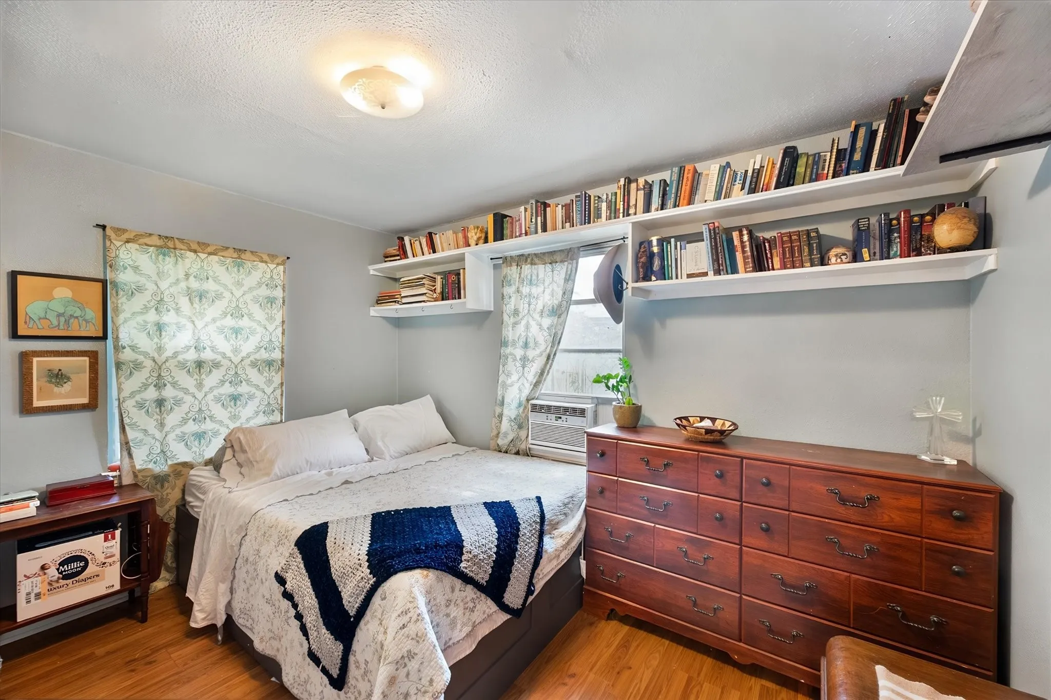 Wood-finish flooring with built-in shelving, two windows, and overhead lighting