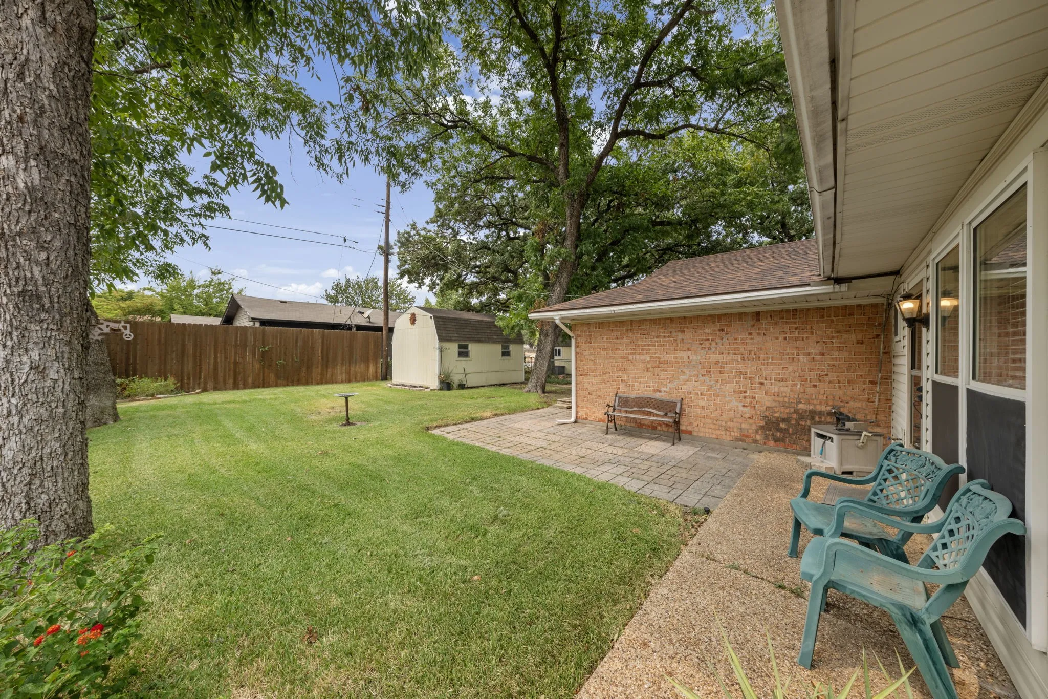 Expansive lawn with mature trees and wood fencing