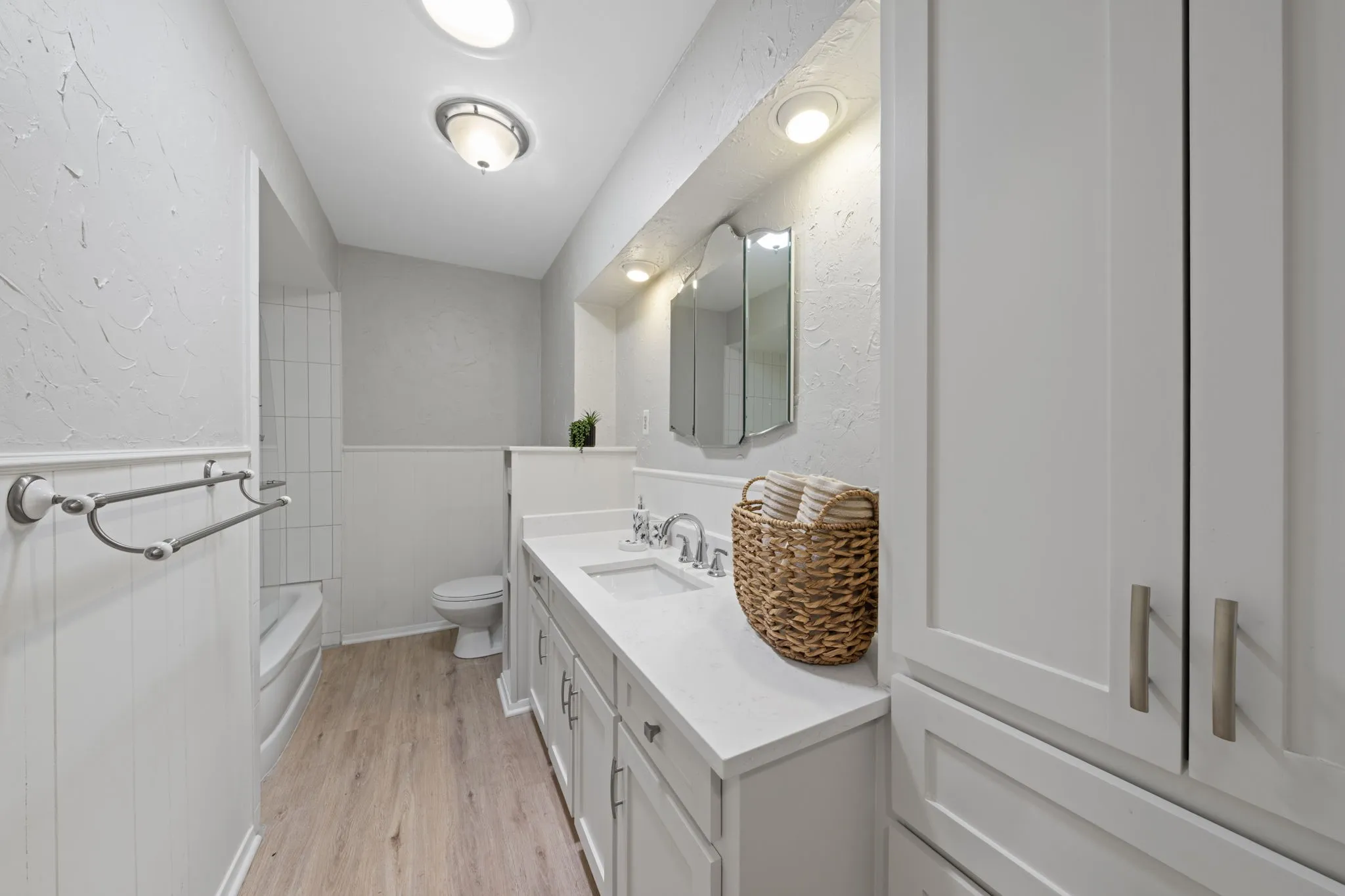 Bathroom with a vanity featuring an integrated sink, a built-in medicine cabinet, recessed lighting, and wood-finish flooring
