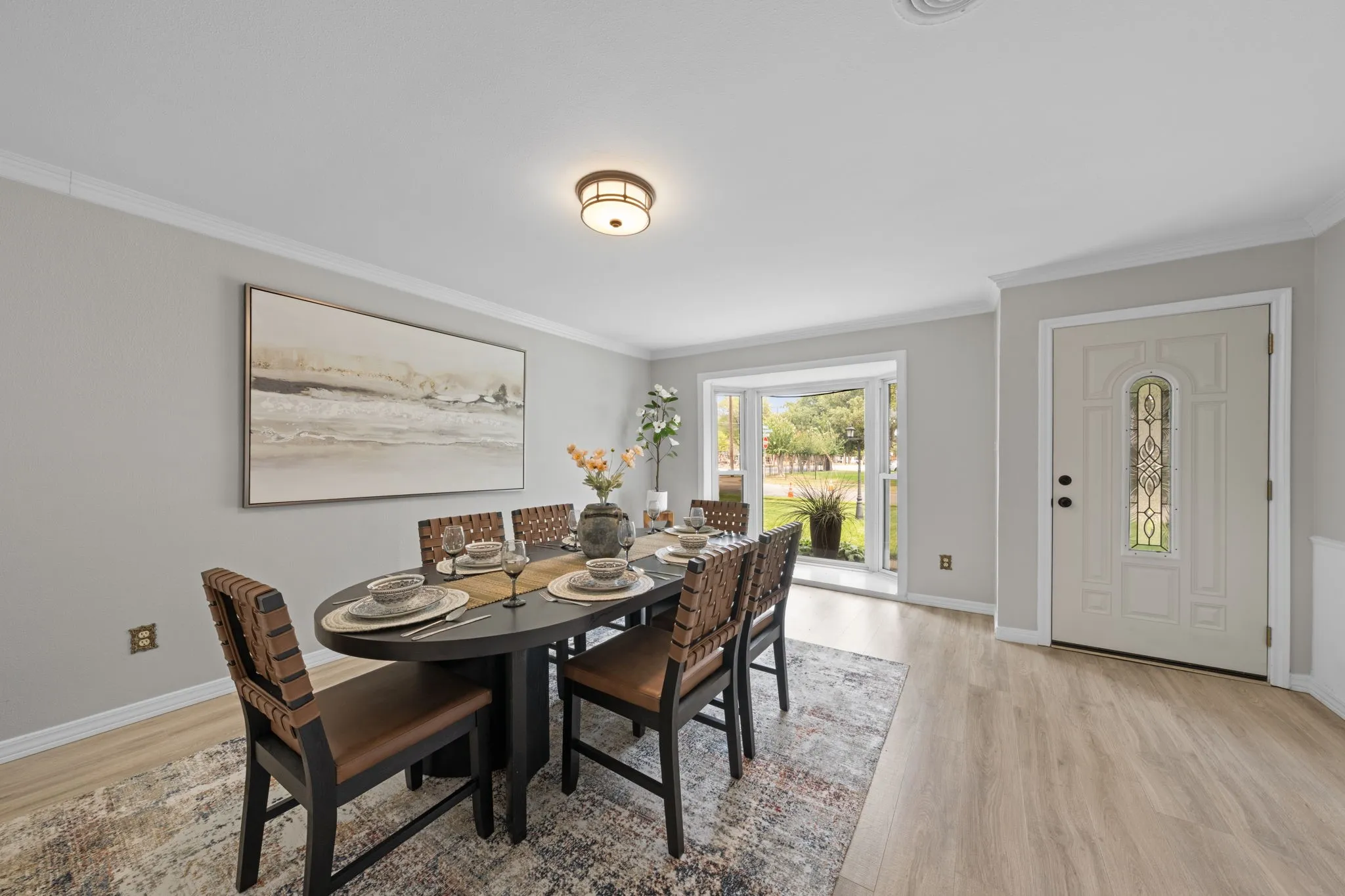 Crown molding details, recessed lighting, wood-finish flooring, bay window, and a decorative glass front door