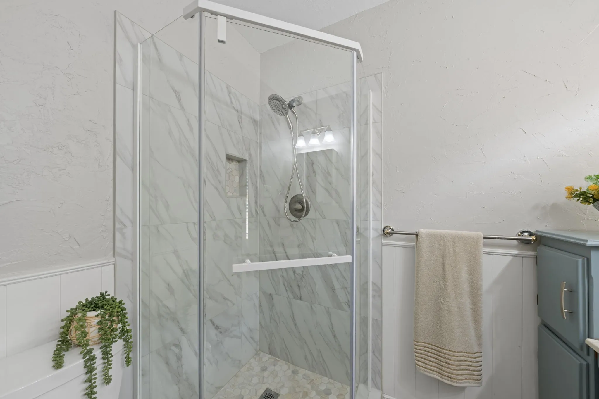 Glass-enclosed shower with a tiled interior, a recessed shelf, and a rainfall showerhead
