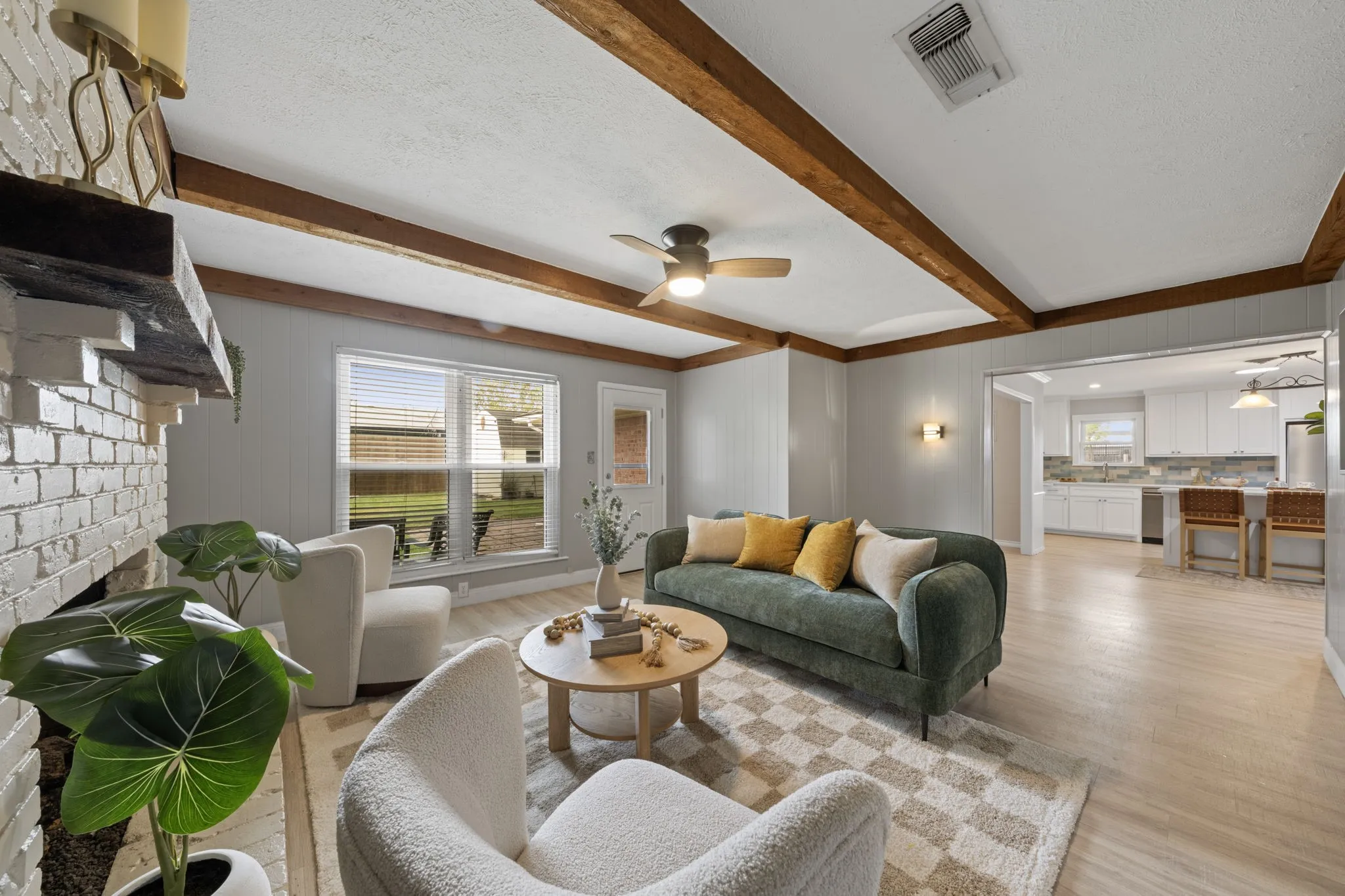 Living area featuring exposed ceiling beams, a painted brick fireplace, a ceiling fan with integrated lighting, wood-finish flooring, and recessed lighting