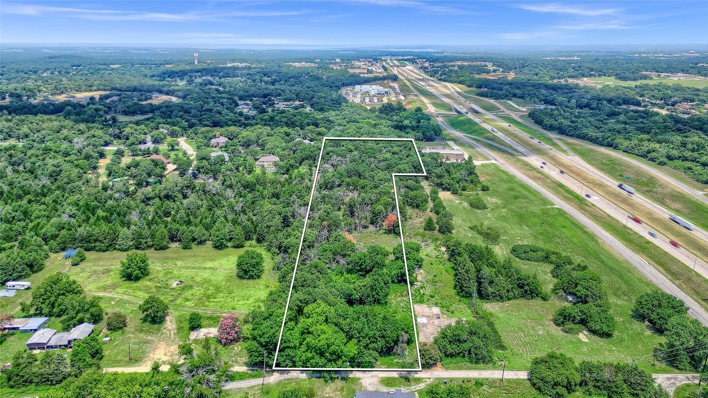 Expansive land parcel featuring dense tree coverage and partial highway frontage