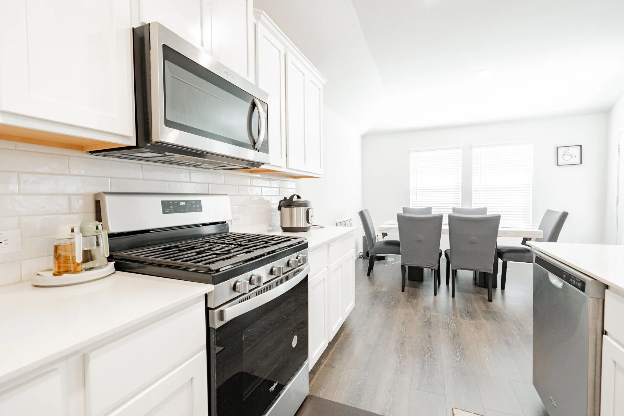 Kitchen featuring white cabinetry, stainless steel appliances, subway tile backsplash, and light-toned countertops