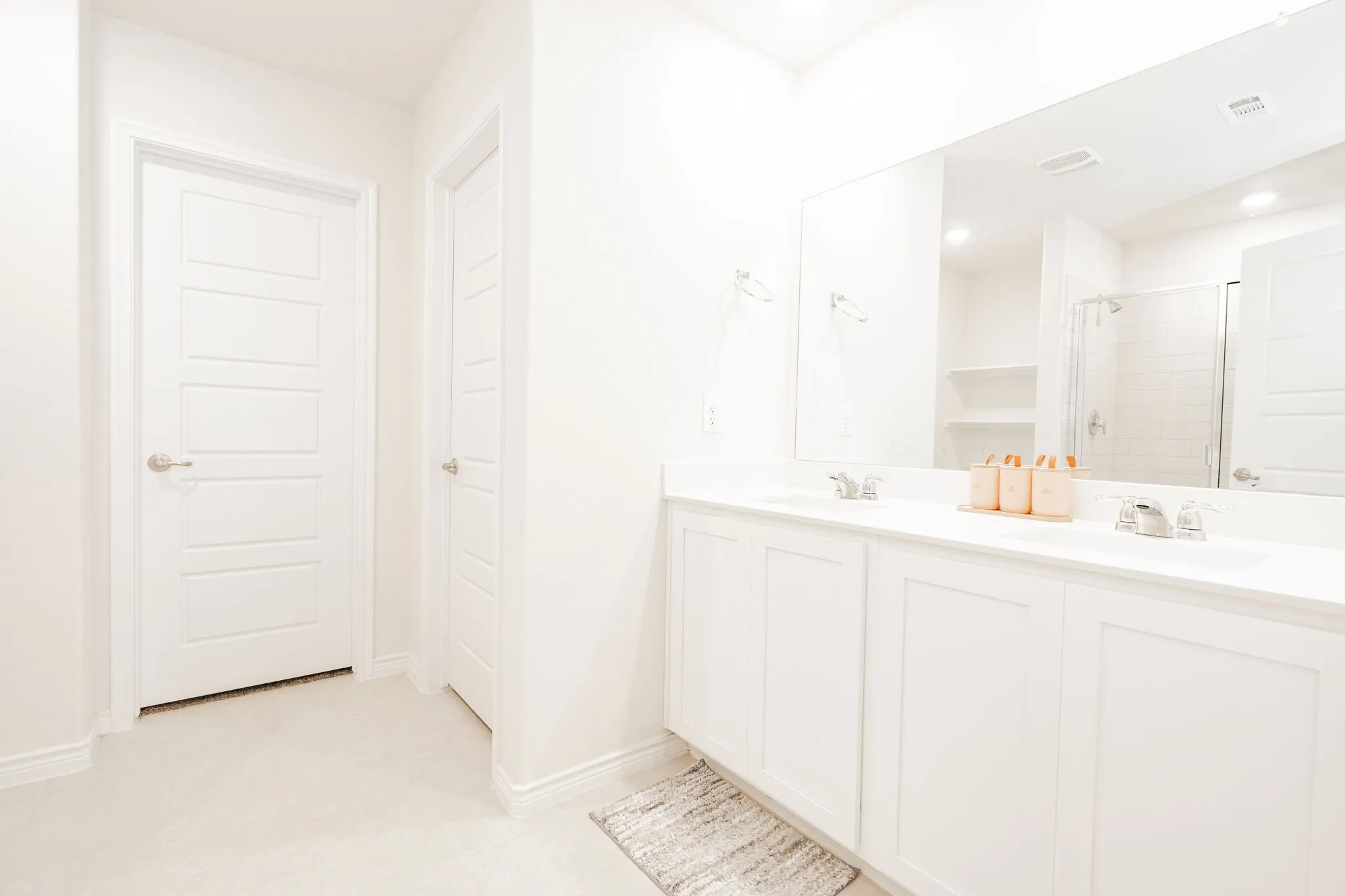 Double vanity with undermount sinks, expansive mirror, and integrated storage cabinetry