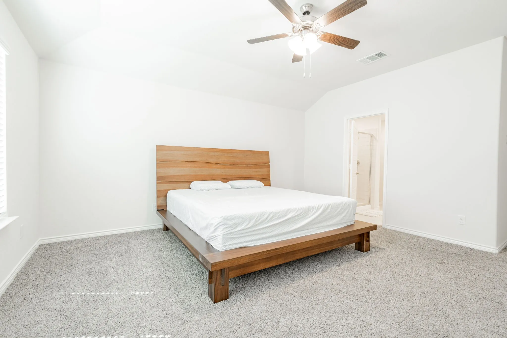 Vaulted ceiling, ceiling fan, plush carpet flooring, window with blinds, and white wall finishes