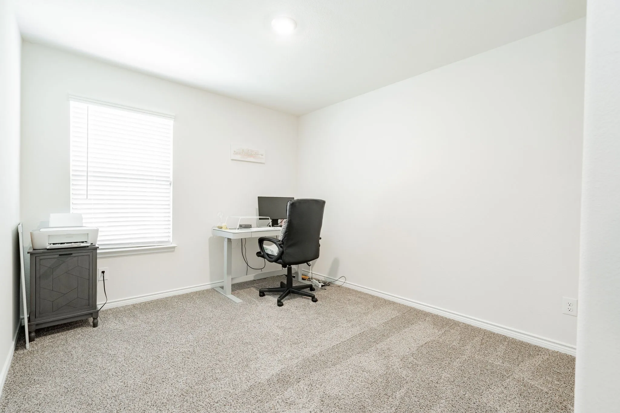 Carpeted room featuring a single window with horizontal blinds, white walls, and a ceiling light fixture