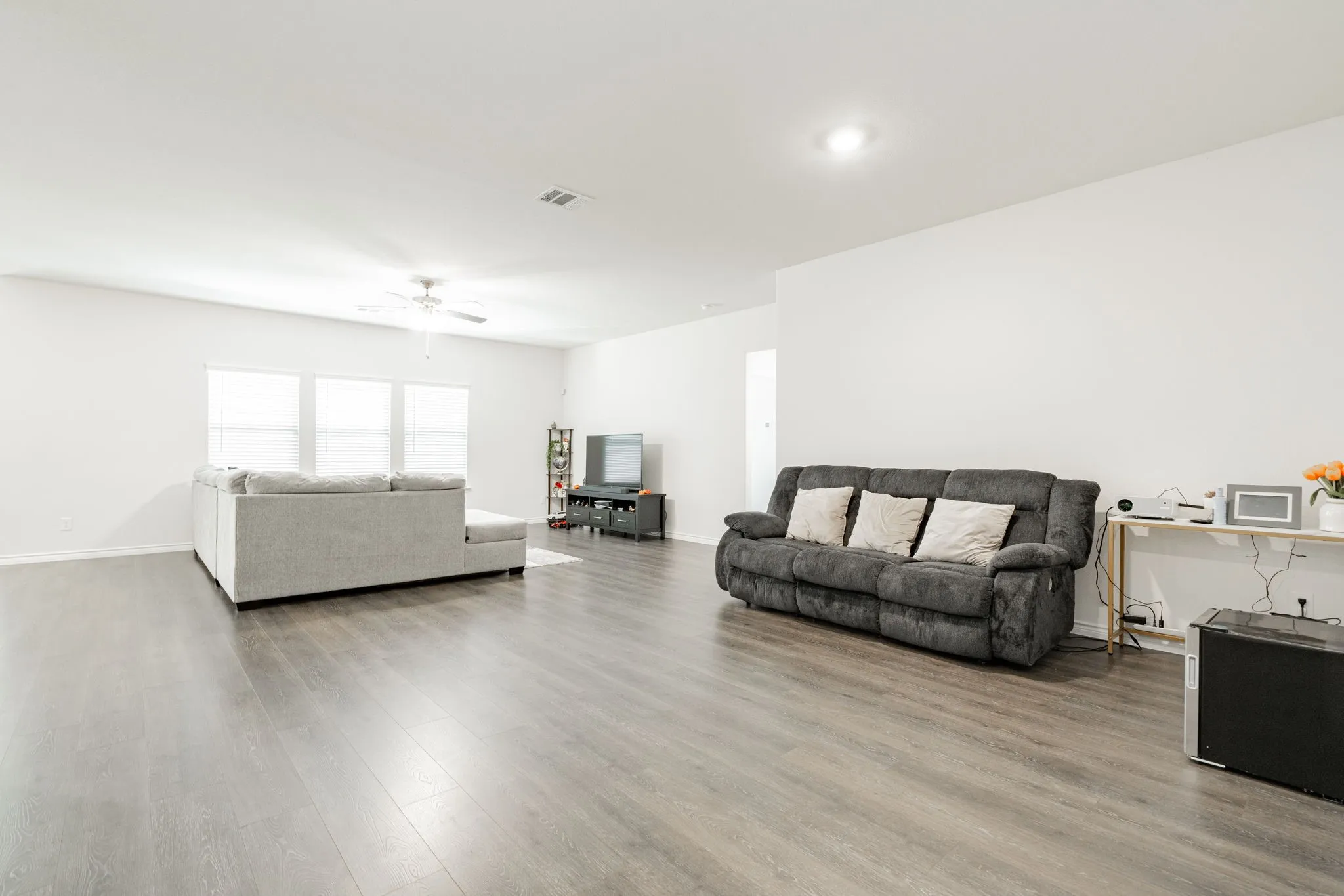 Spacious living area featuring wood-finish flooring, recessed lighting, and a ceiling fan