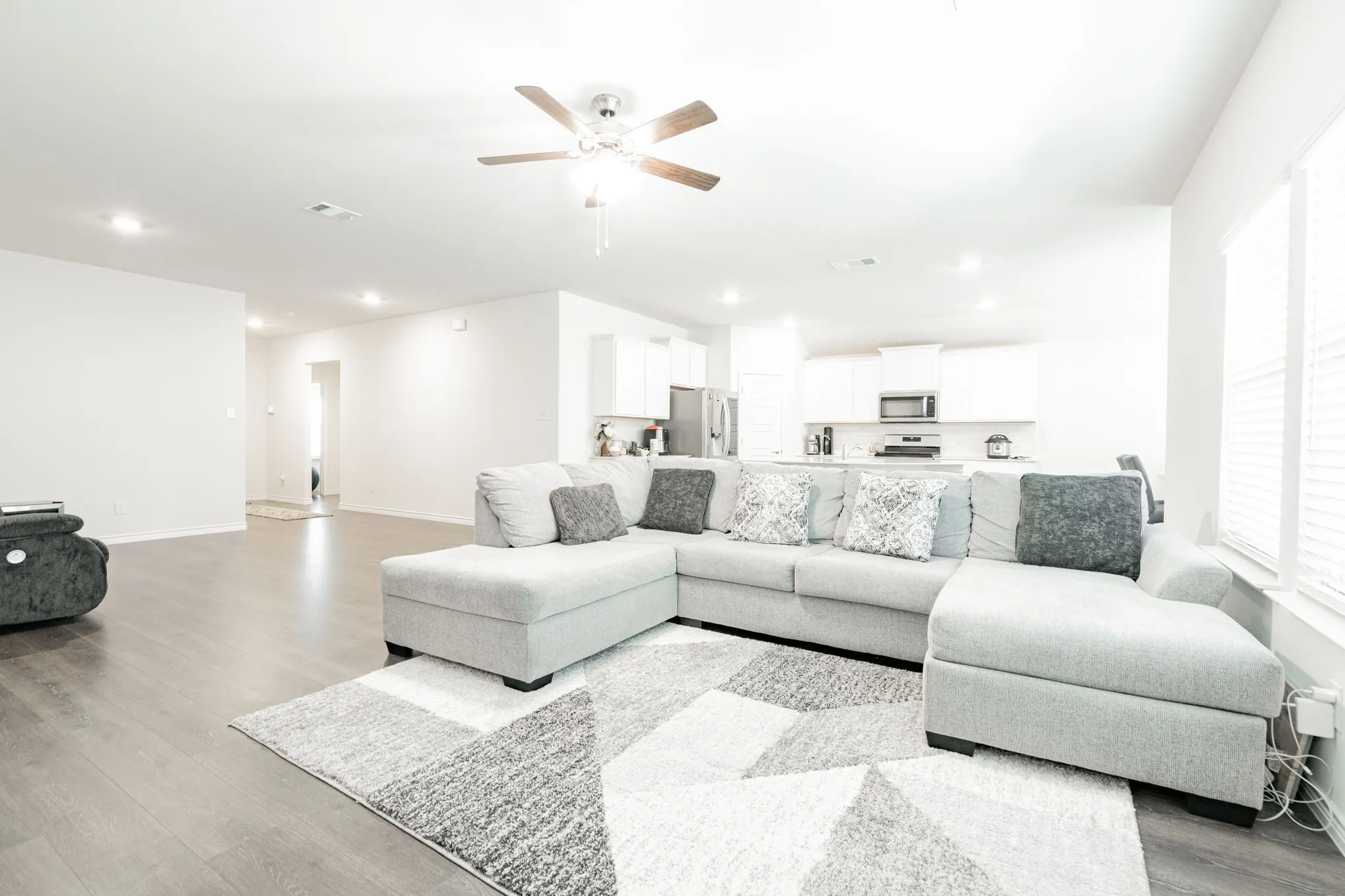 Open-concept living area with wood-finish flooring, recessed lighting, and a ceiling fan
