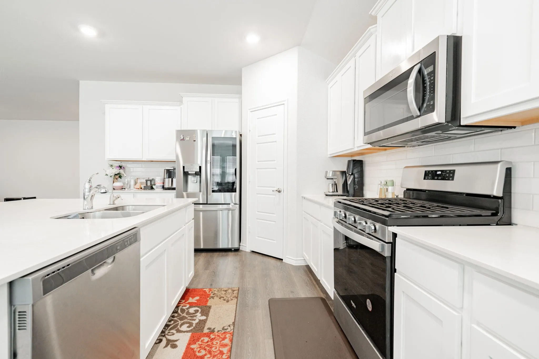 White cabinetry, stainless steel appliances, and a kitchen island with an undermount sink