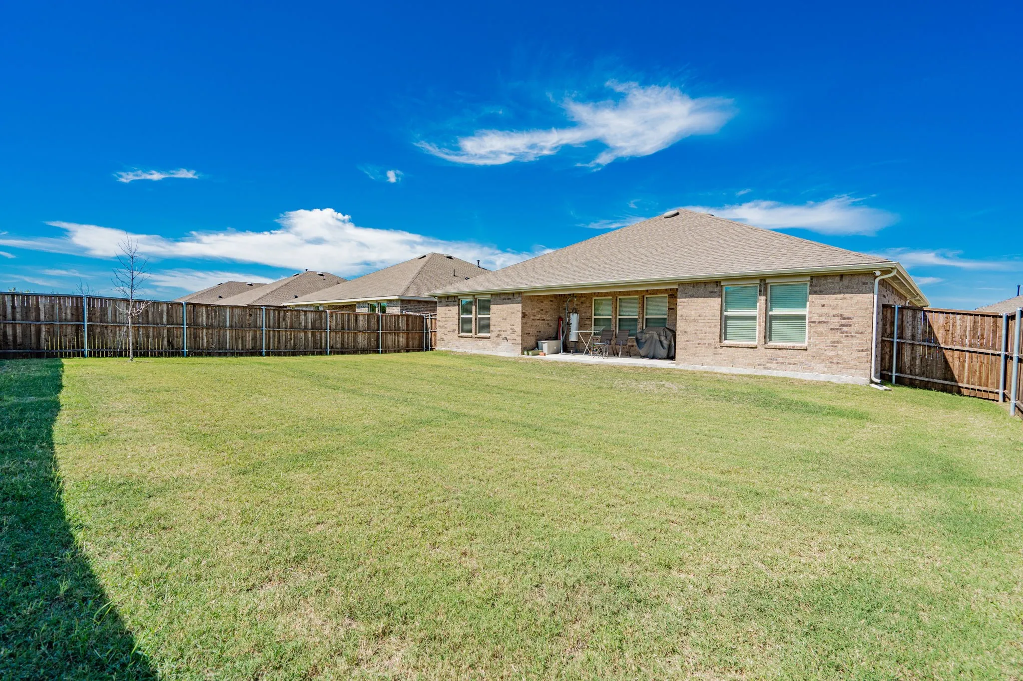 Expansive grassy yard with wood fencing and a brick exterior