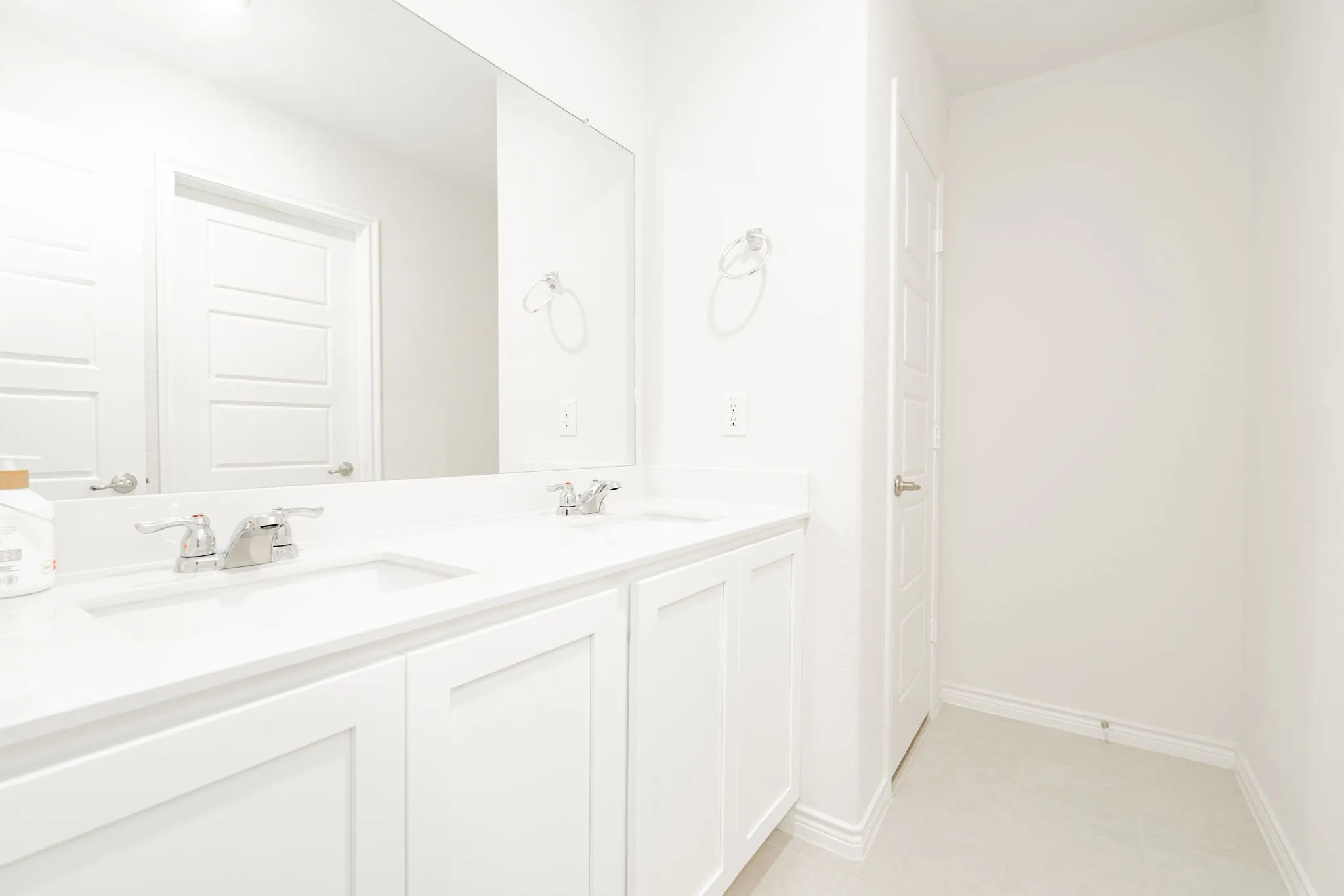 Double vanity with undermount sinks, chrome faucets, and white cabinetry