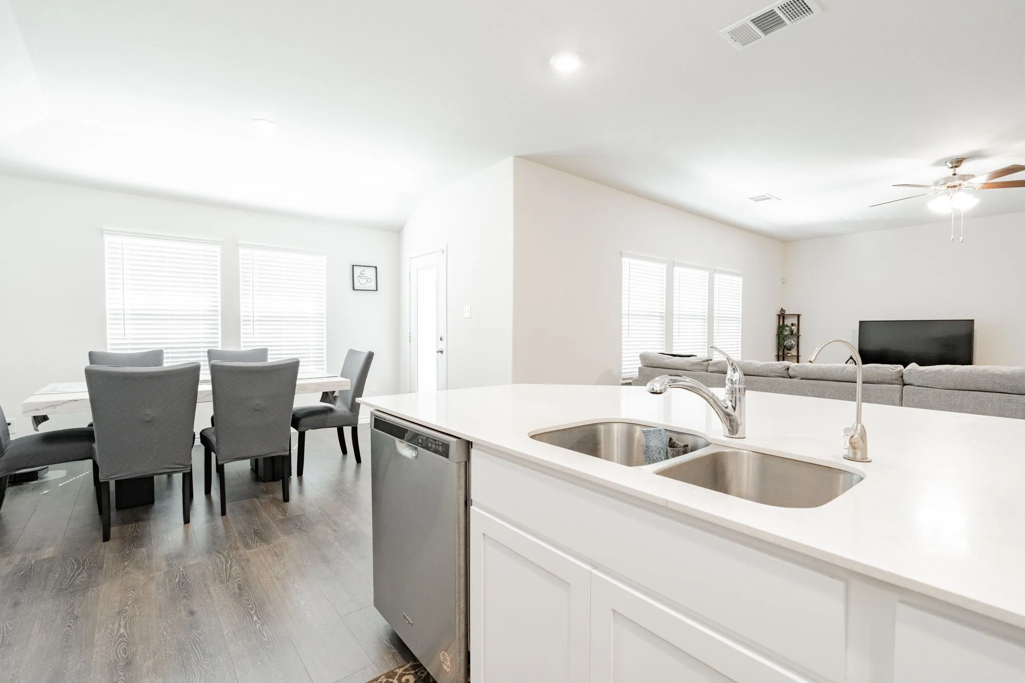 Kitchen island with a double basin stainless steel sink, stainless steel dishwasher, and white cabinetry