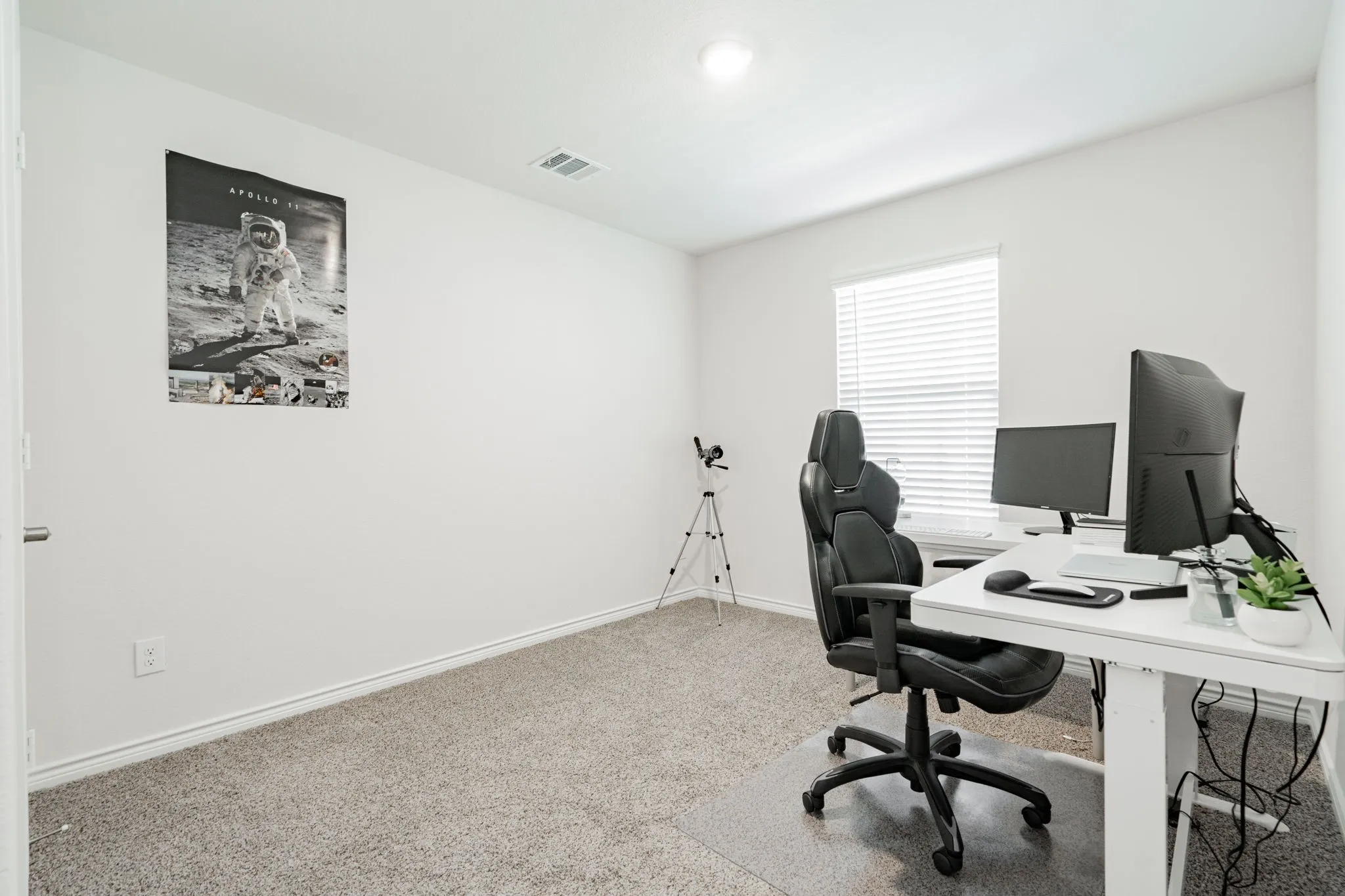 Carpeted room with white walls, a single window with blinds, and an overhead light fixture