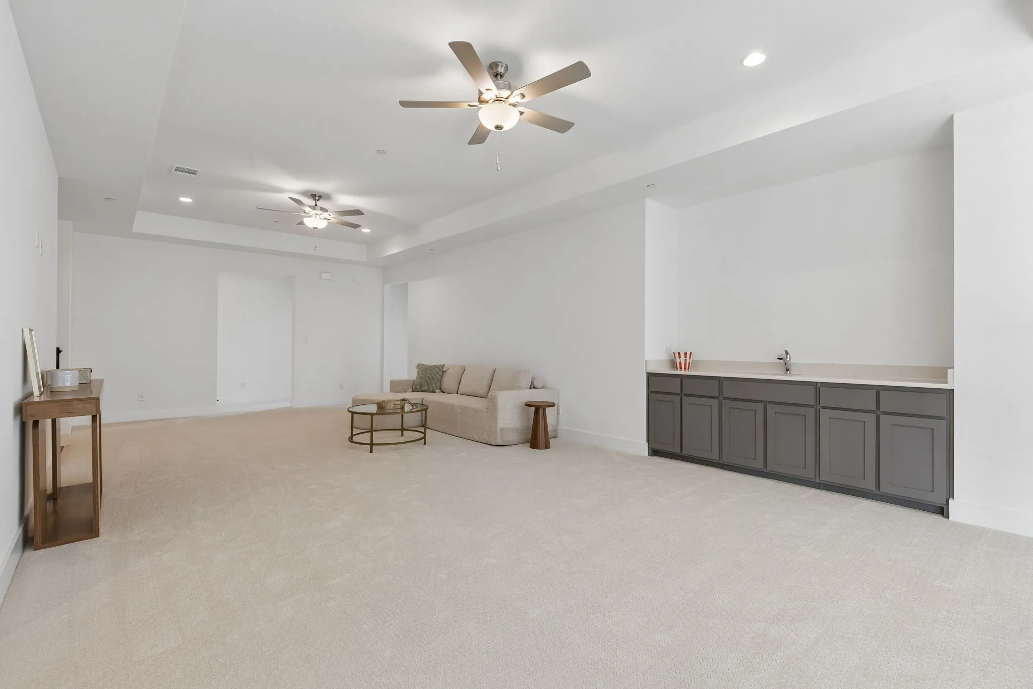 Expansive carpeted area featuring a built-in wet bar with a countertop and under-cabinet storage, and recessed lighting