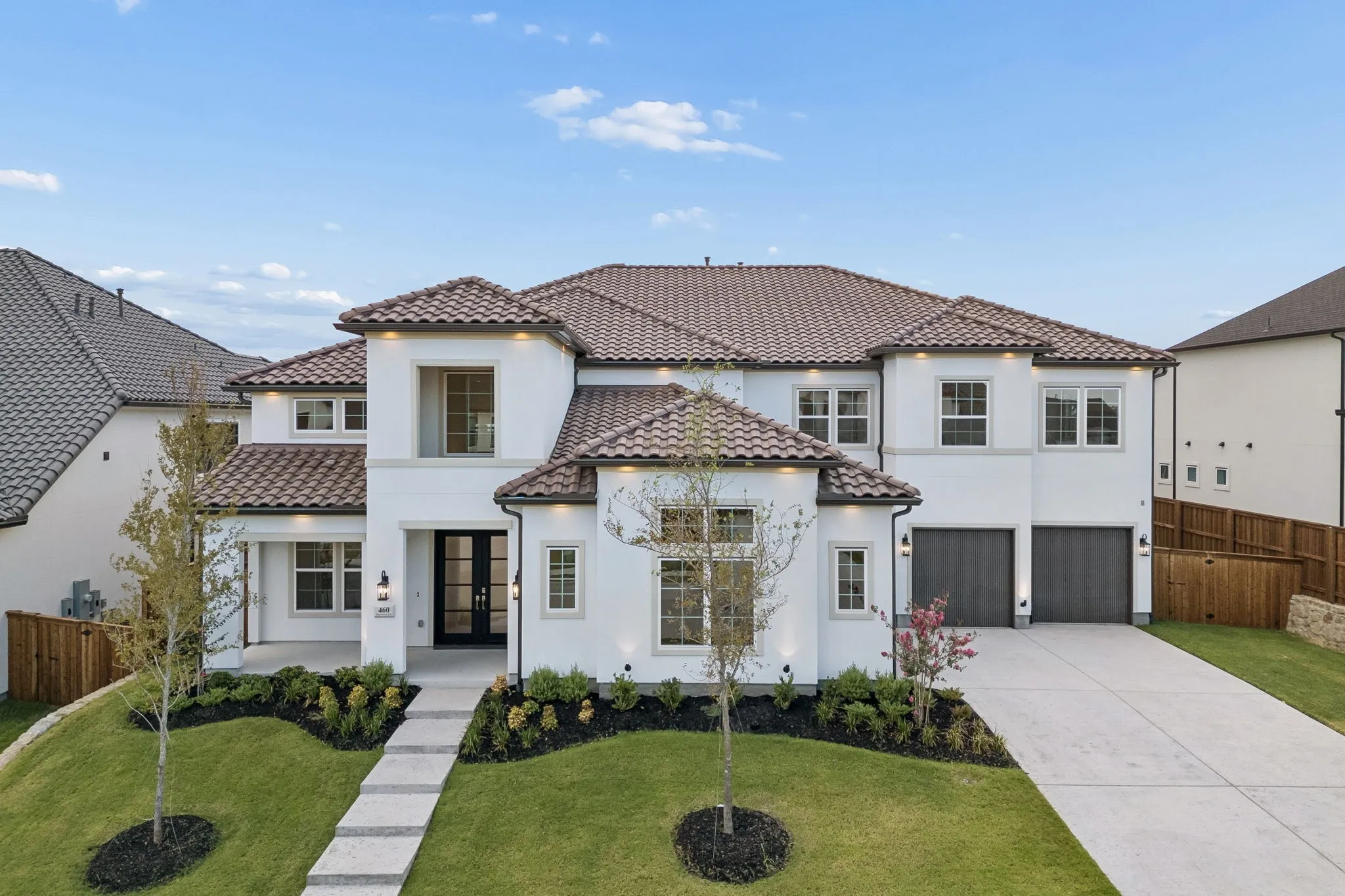 Stucco exterior with a tile roof, featuring a concrete driveway and an attached two-car garage