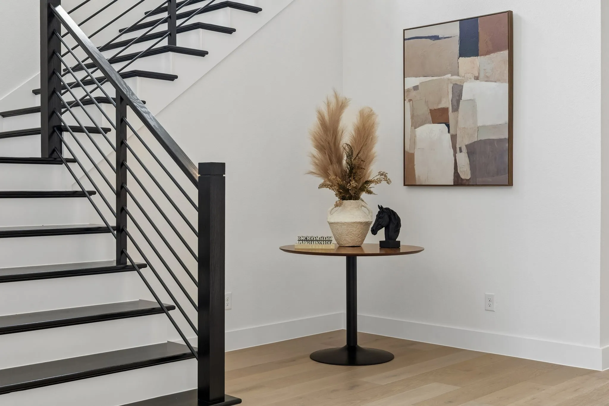 Modern staircase featuring black metal railings with horizontal cable detailing and wood-finish treads