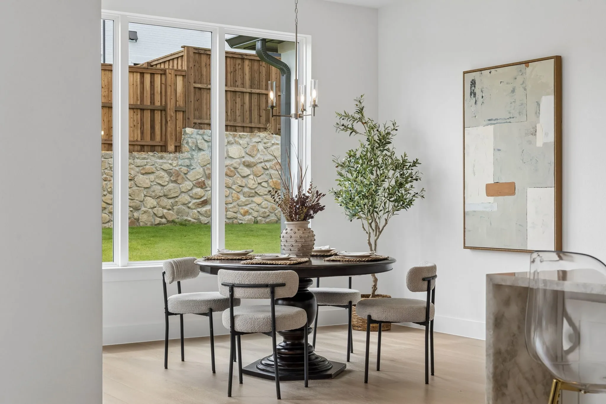 Expansive window overlooking a stone retaining wall and fenced yard