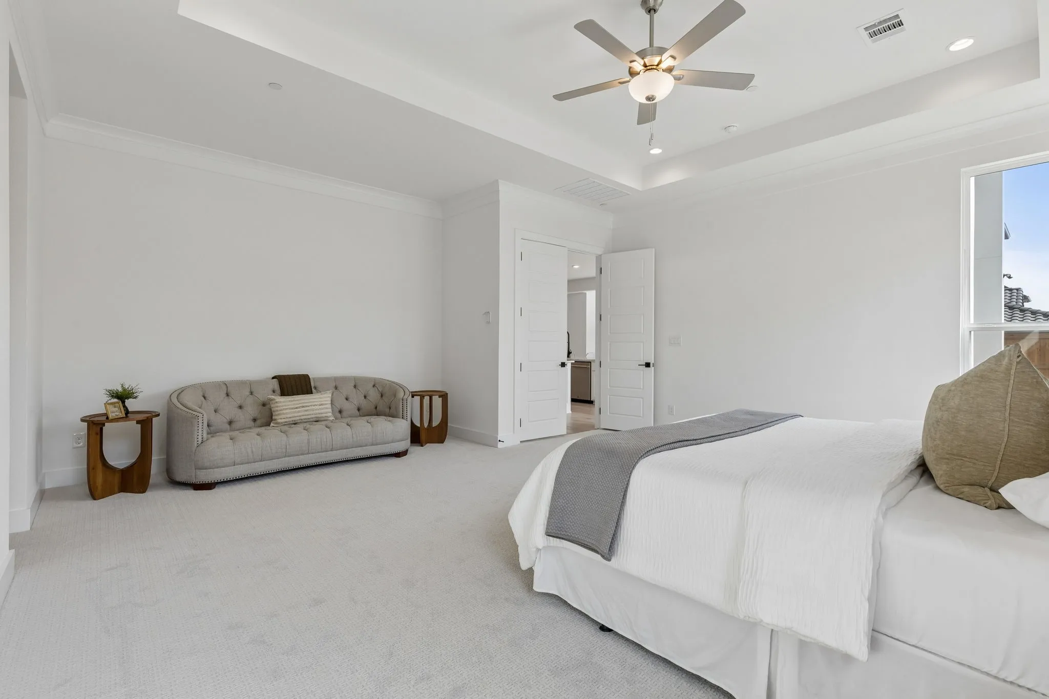 Tray ceiling with recessed lighting, ceiling fan, white paneled doors, and carpet flooring