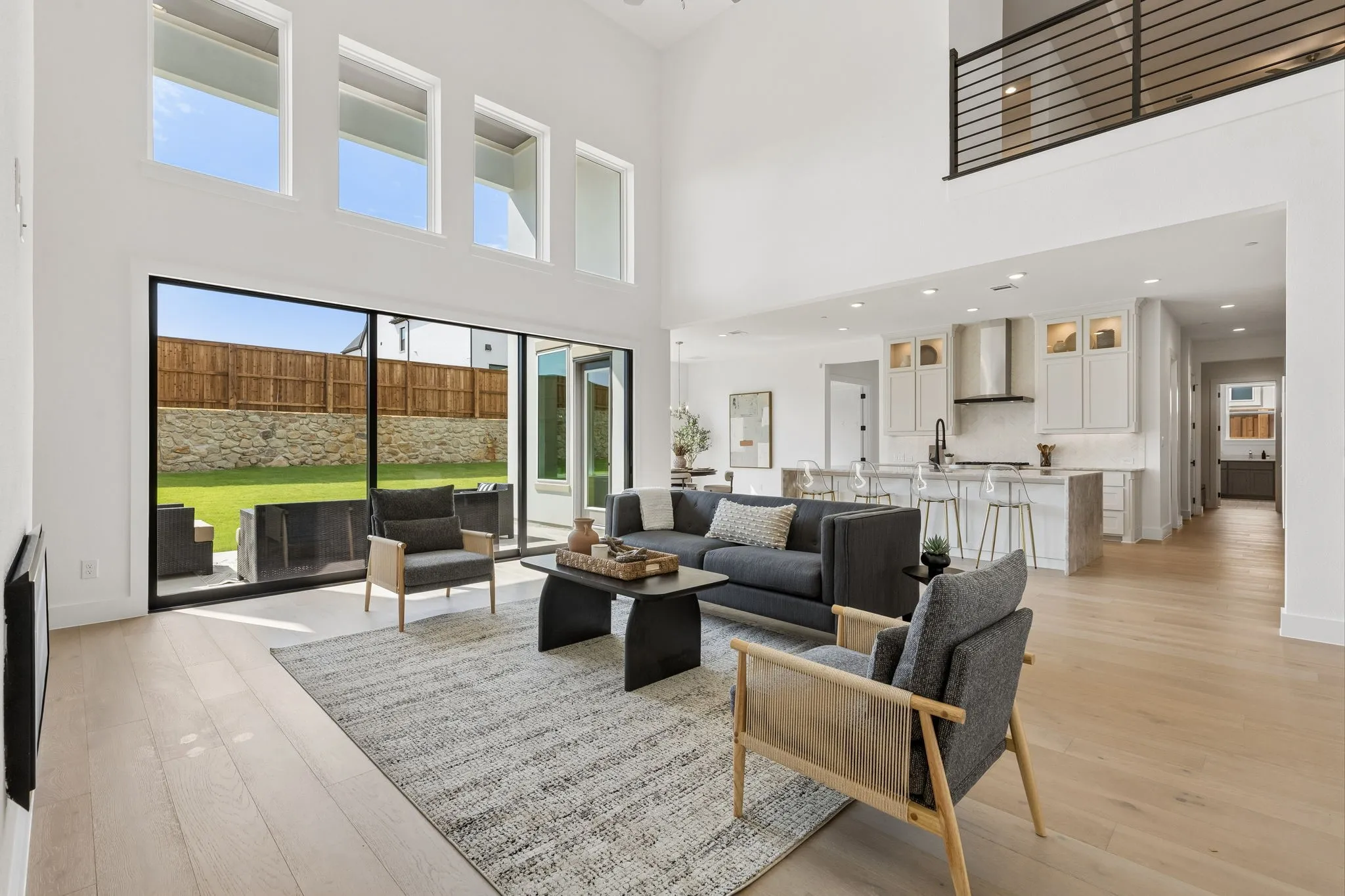 Two-story great room with high ceilings, large windows, wood-finish flooring, and a kitchen featuring a large island