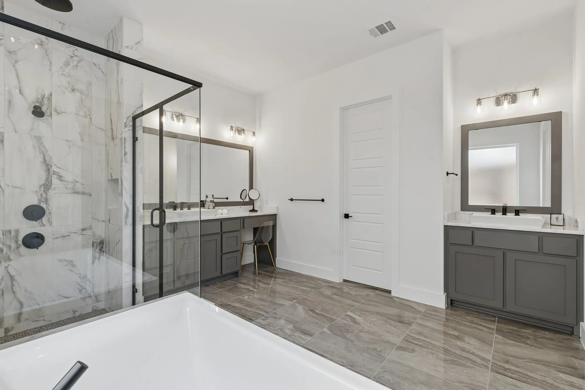 Walk-in shower with marble-look tile surround and black-framed glass enclosure
