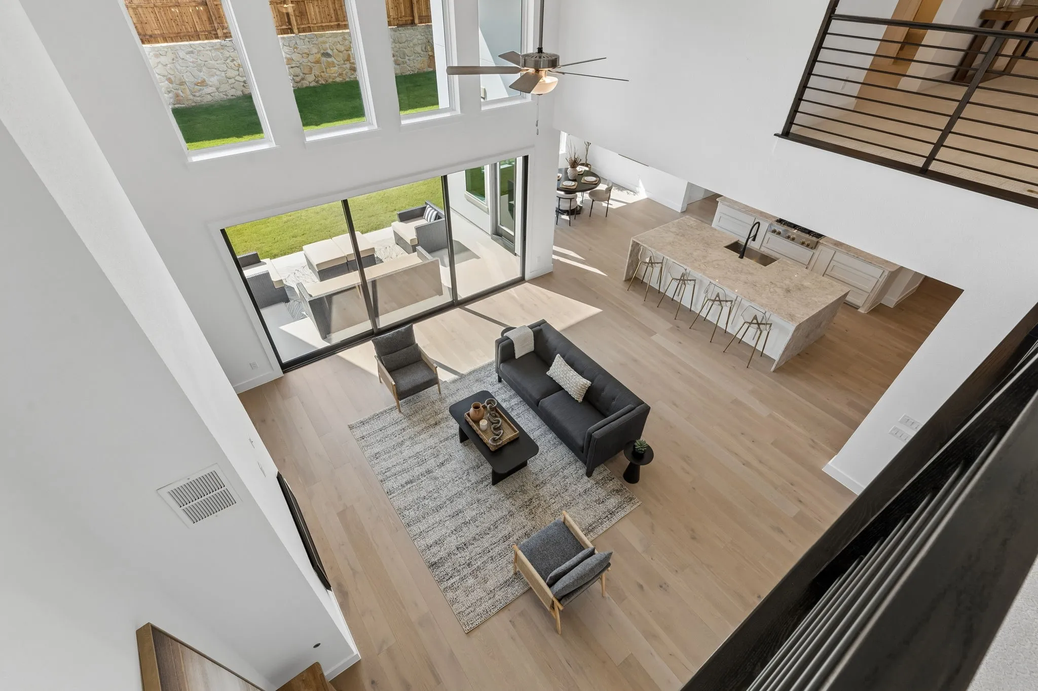 Soaring ceilings with transom windows, expansive sliding glass doors, light wood-finish flooring, a kitchen island with seating, and a modern open-concept layout
