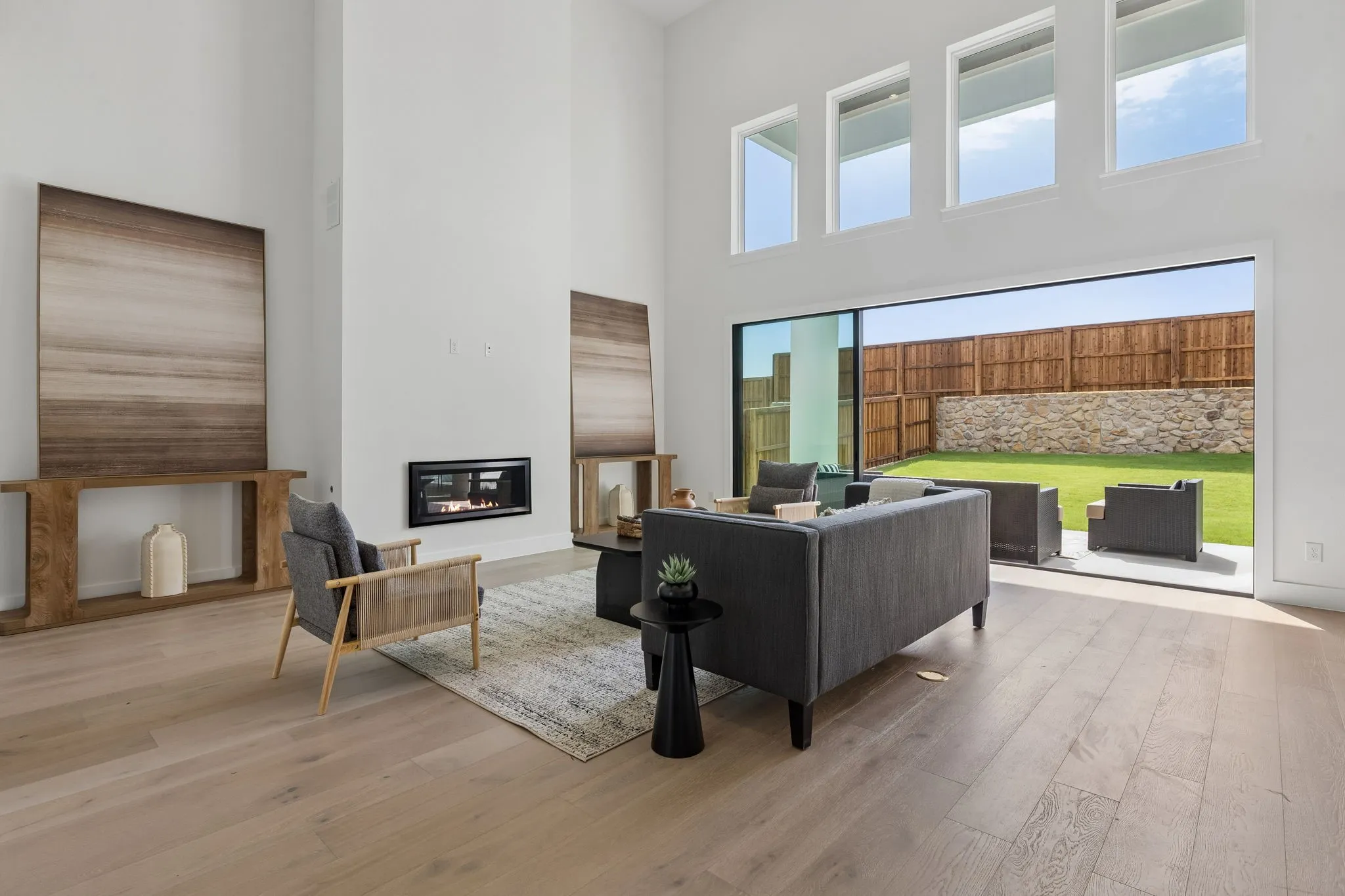 Expansive living area featuring soaring ceilings, a linear fireplace, and wood-finish flooring